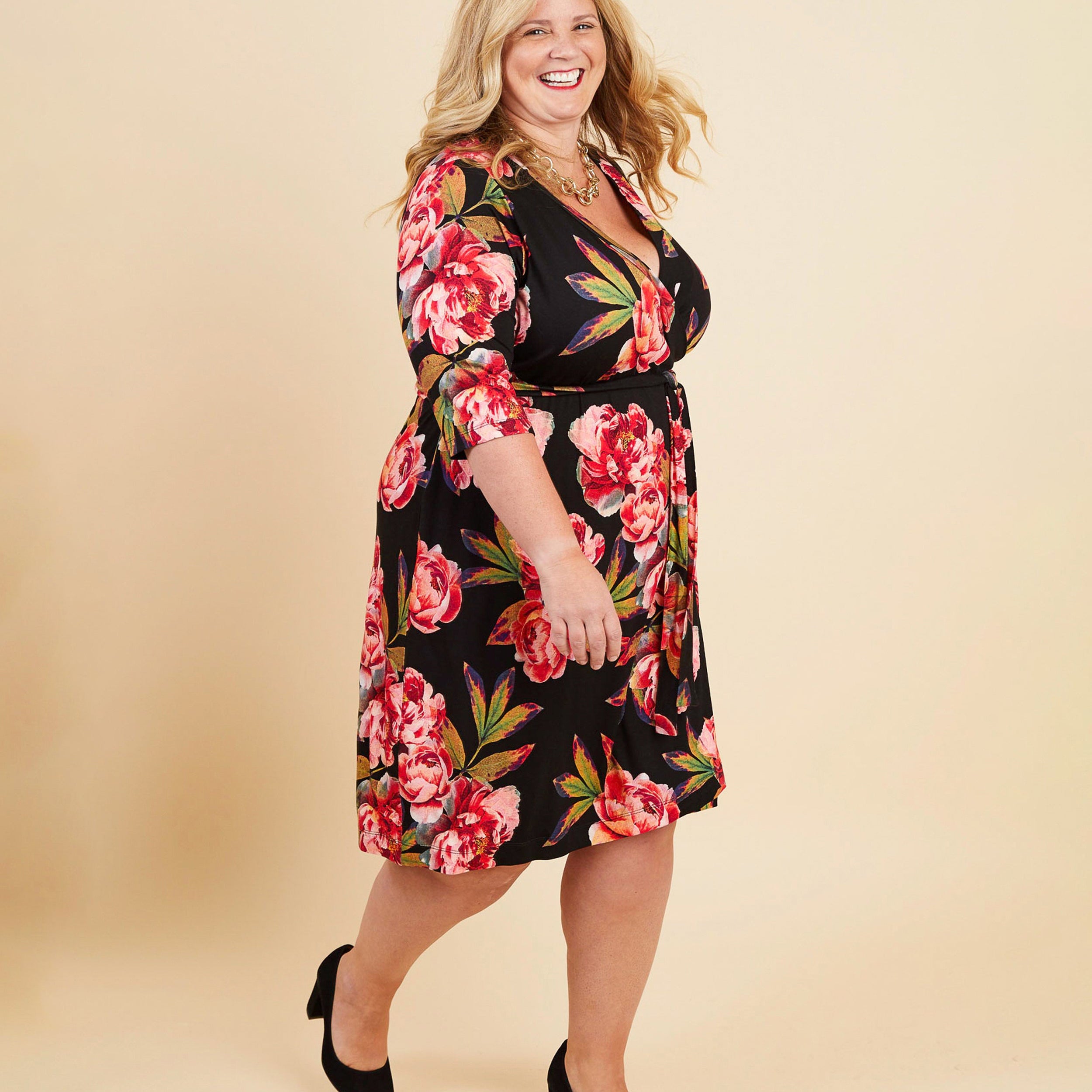 Woman wearing a floral dress on a beige background. This dress is the Appleton Wrap Dress sewing pattern from Cashmerette.