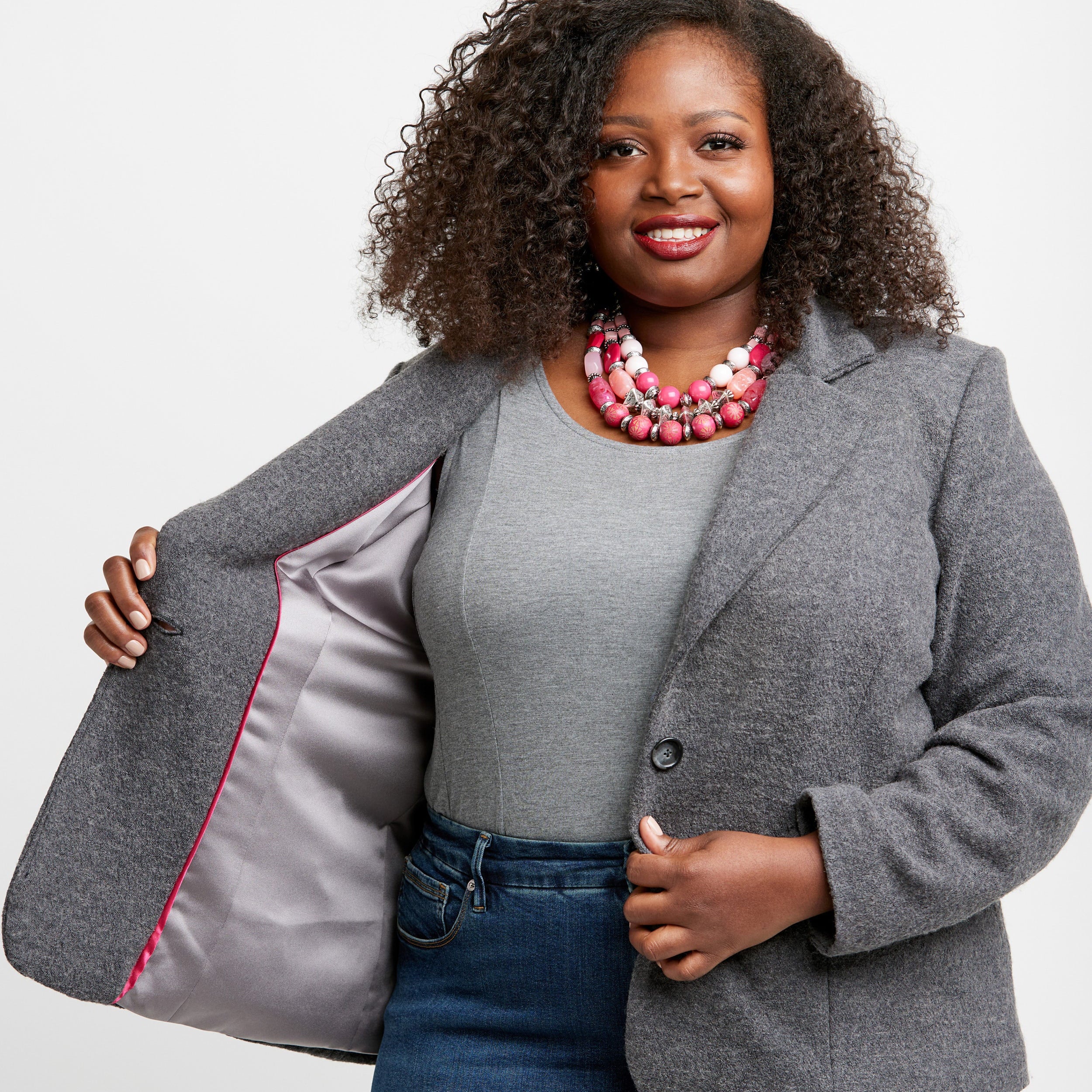 Woman wearing a gray blazer with a red interior lining, standing against a plain background. This blazer is the Auburn Blazer sewing pattern from Cashmerette.