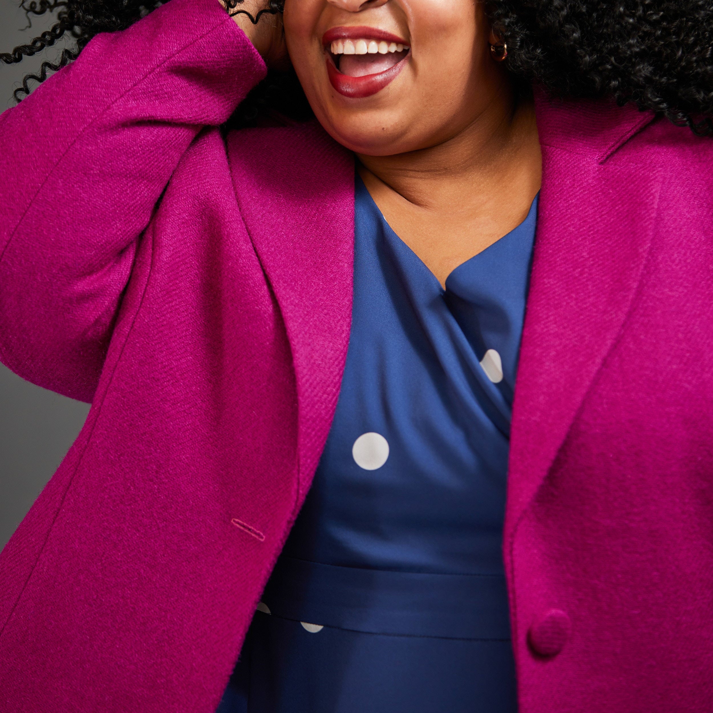 Woman wearing a bright pink blazer over a blue dress with white polka dots. This blazer is the Auburn Blazer sewing pattern from Cashmerette.
