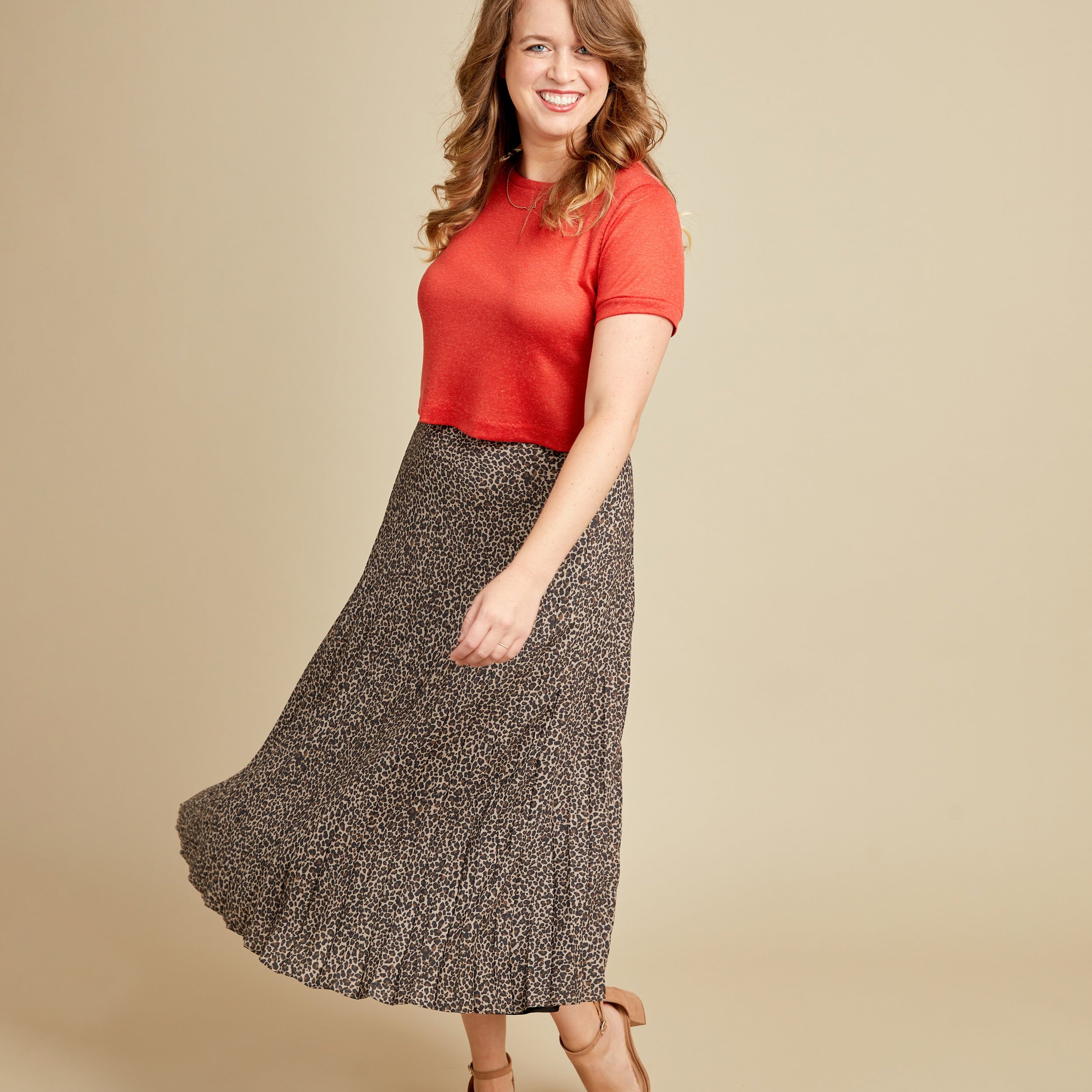 Woman wearing a red top and patterned skirt on a beige background. This t-shirt is the Concord T-Shirt sewing pattern from Cashmerette.