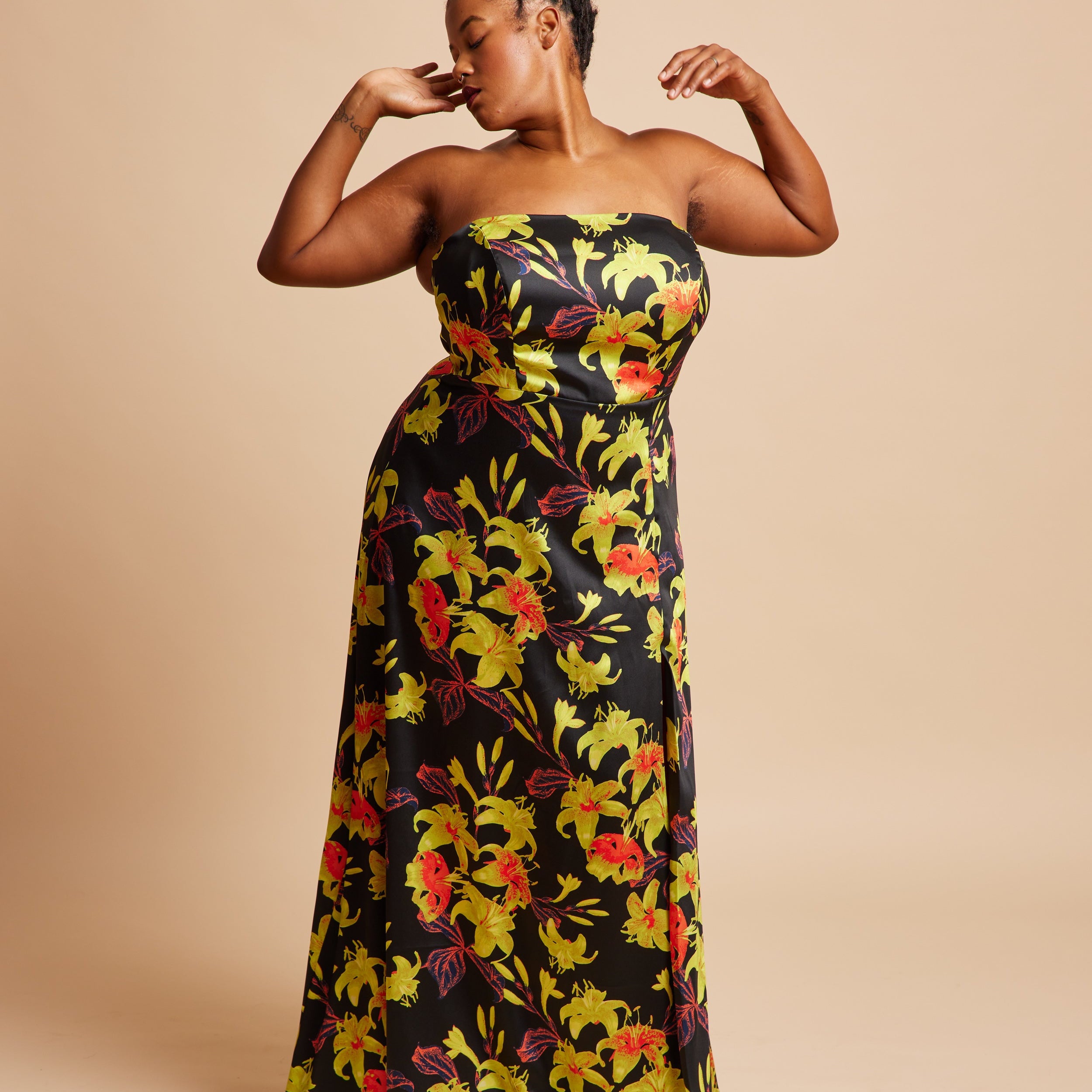 Woman wearing a strapless floral dress on a beige background. This dress is the Ellington Strapless Dress sewing pattern from Cashmerette.