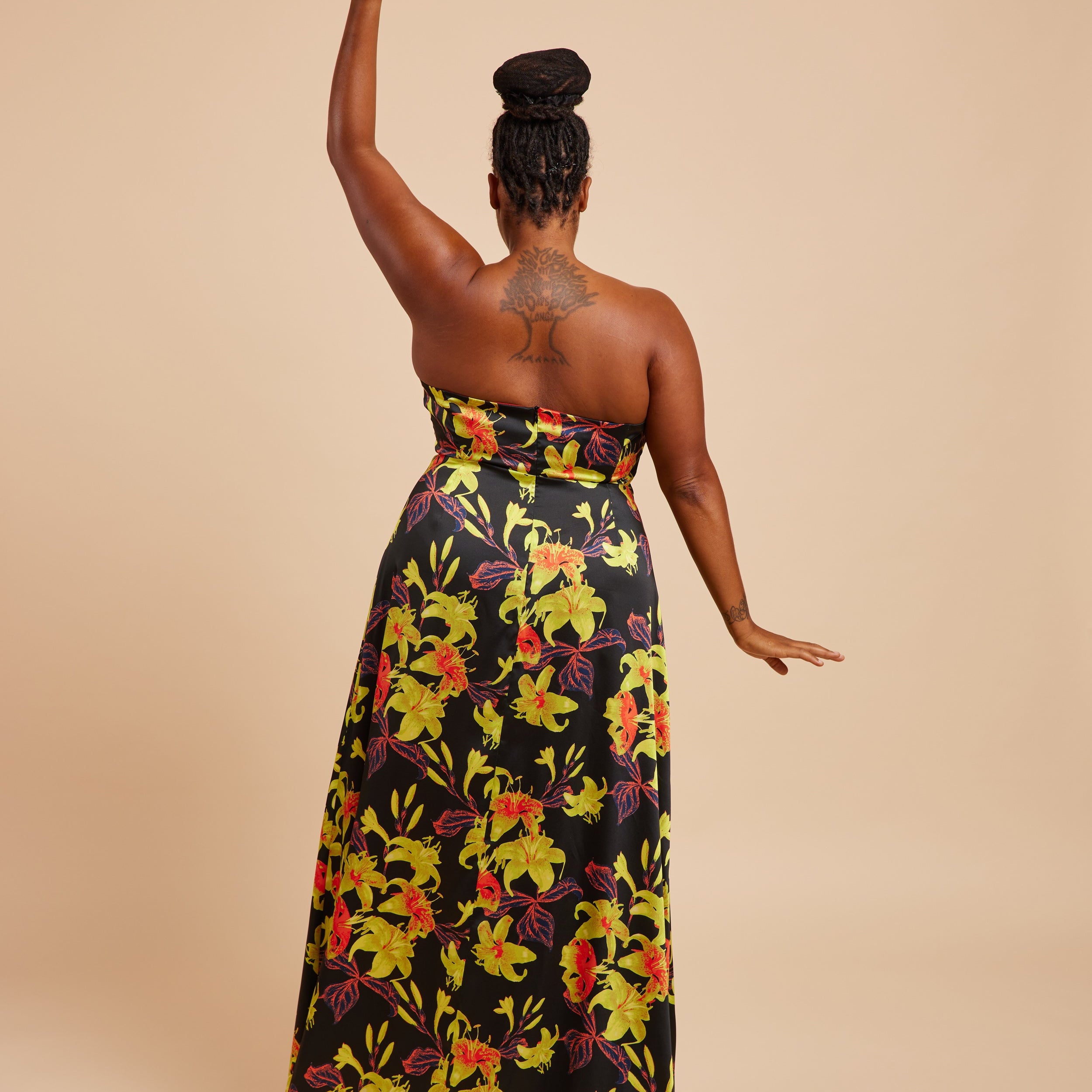 Woman wearing a strapless floral dress with a beige background. This dress is the Ellington Strapless Dress sewing pattern from Cashmerette.