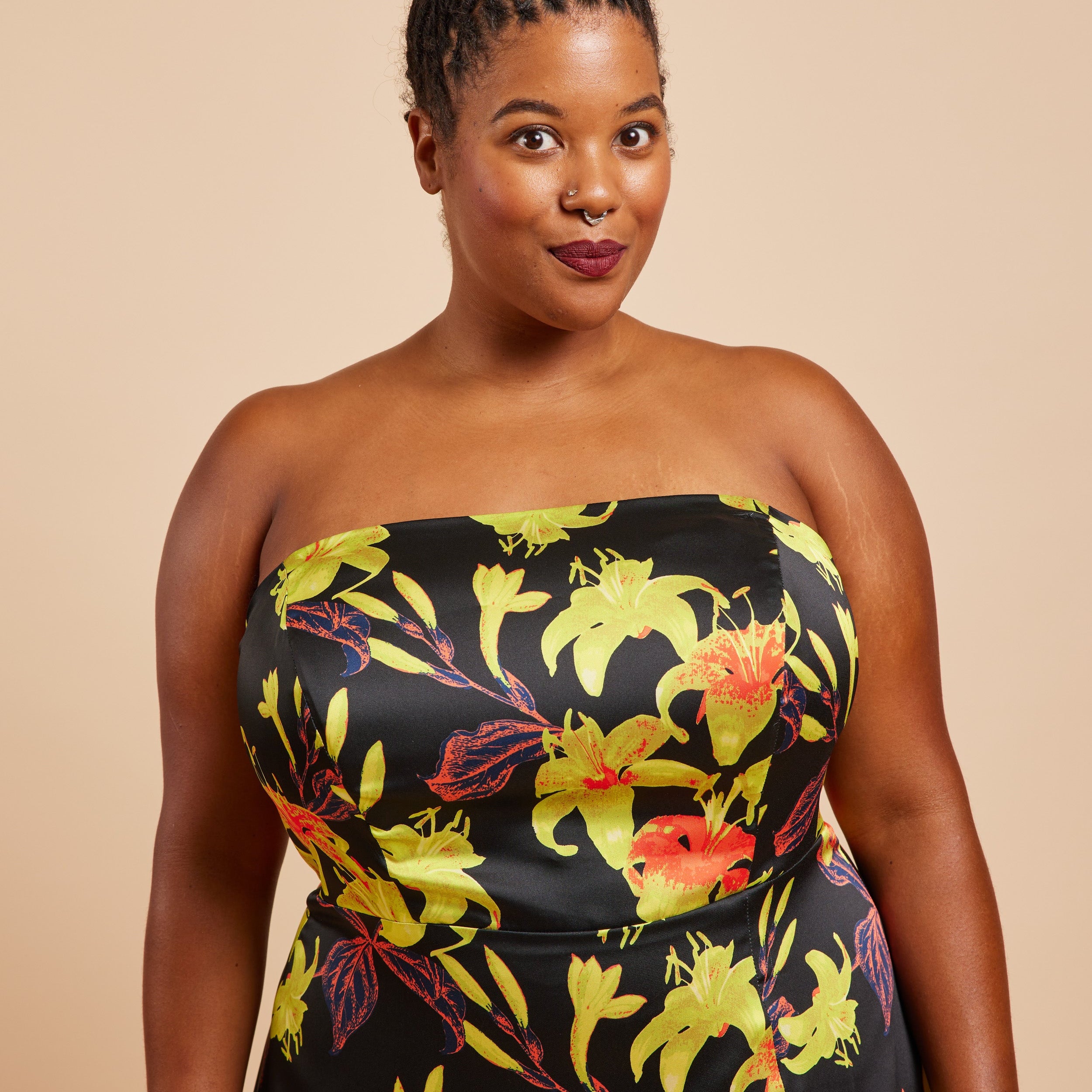 Woman wearing a strapless dress with a floral pattern on a beige background. This dress is the Ellington Strapless Dress sewing pattern from Cashmerette.