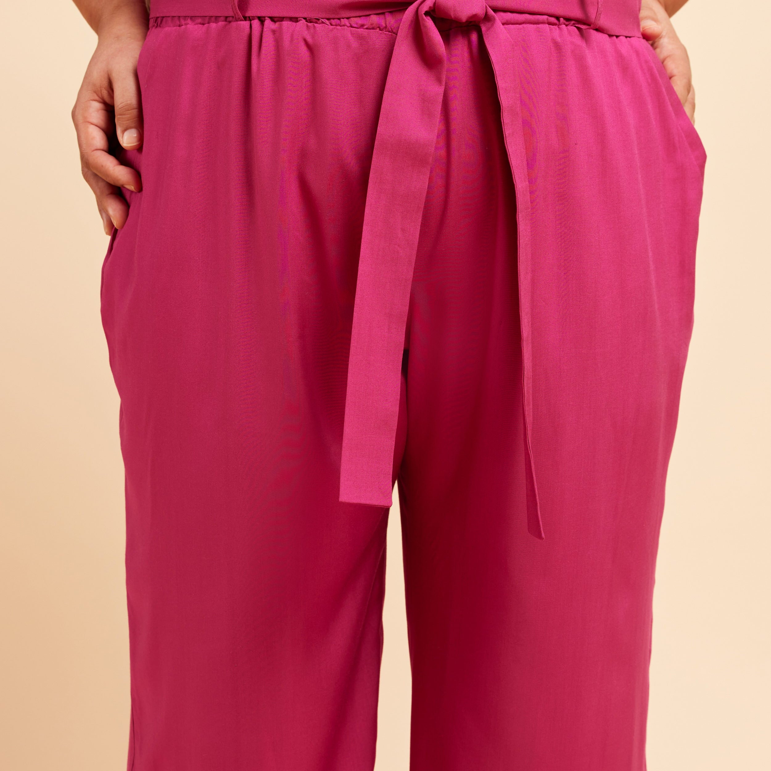Pink pants with a tie waist on a beige background. These pants are the Everett Pants & Shorts sewing pattern from Cashmerette.