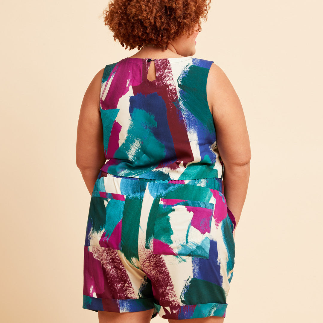 Person wearing a colorful sleeveless top and shorts set on a beige background. These shorts are the Everett Pants & Shorts sewing pattern from Cashmerette.