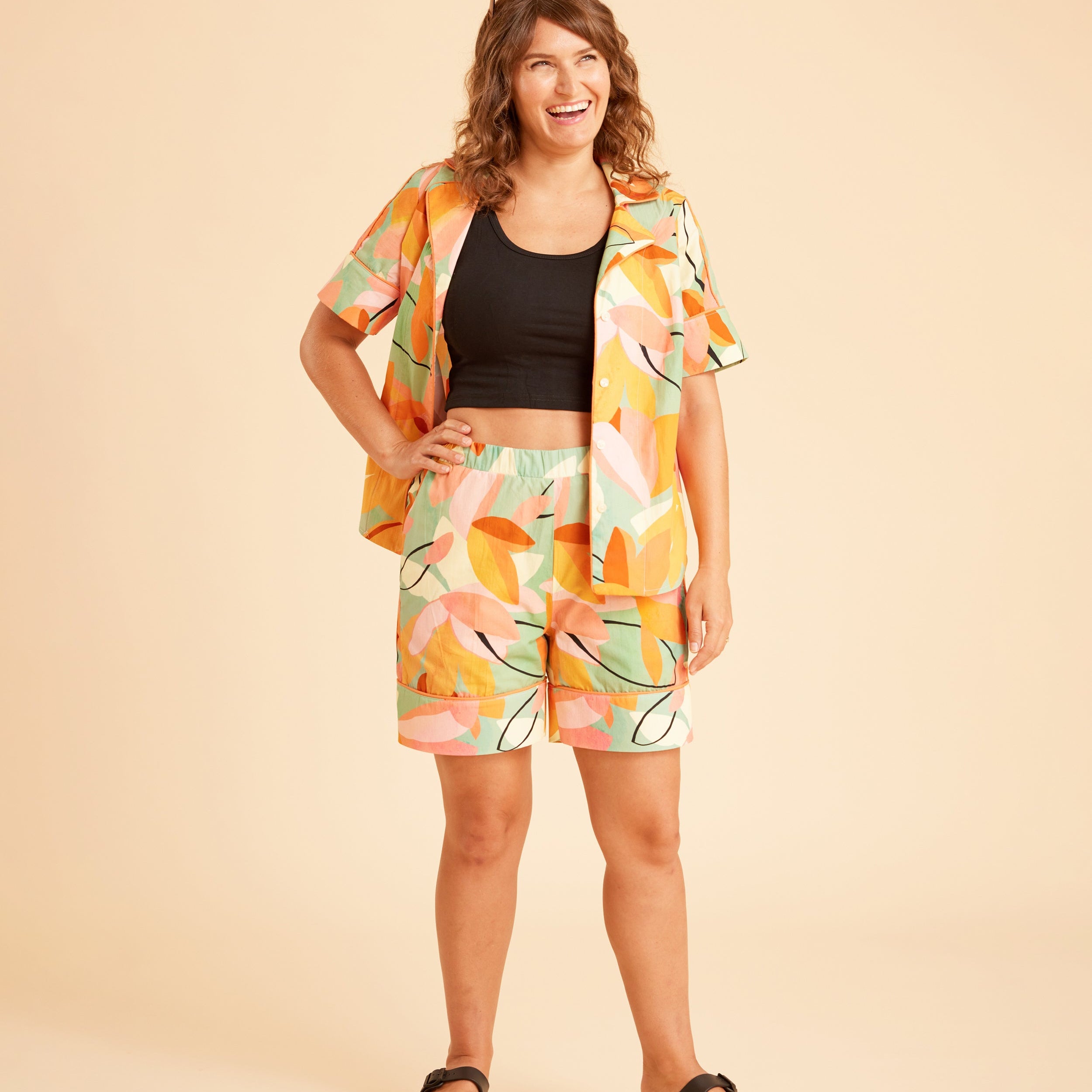 Woman wearing a colorful outfit with a patterned jacket and shorts on a beige background. This is the Fiske Sleepwear Set sewing pattern from Cashmerette.