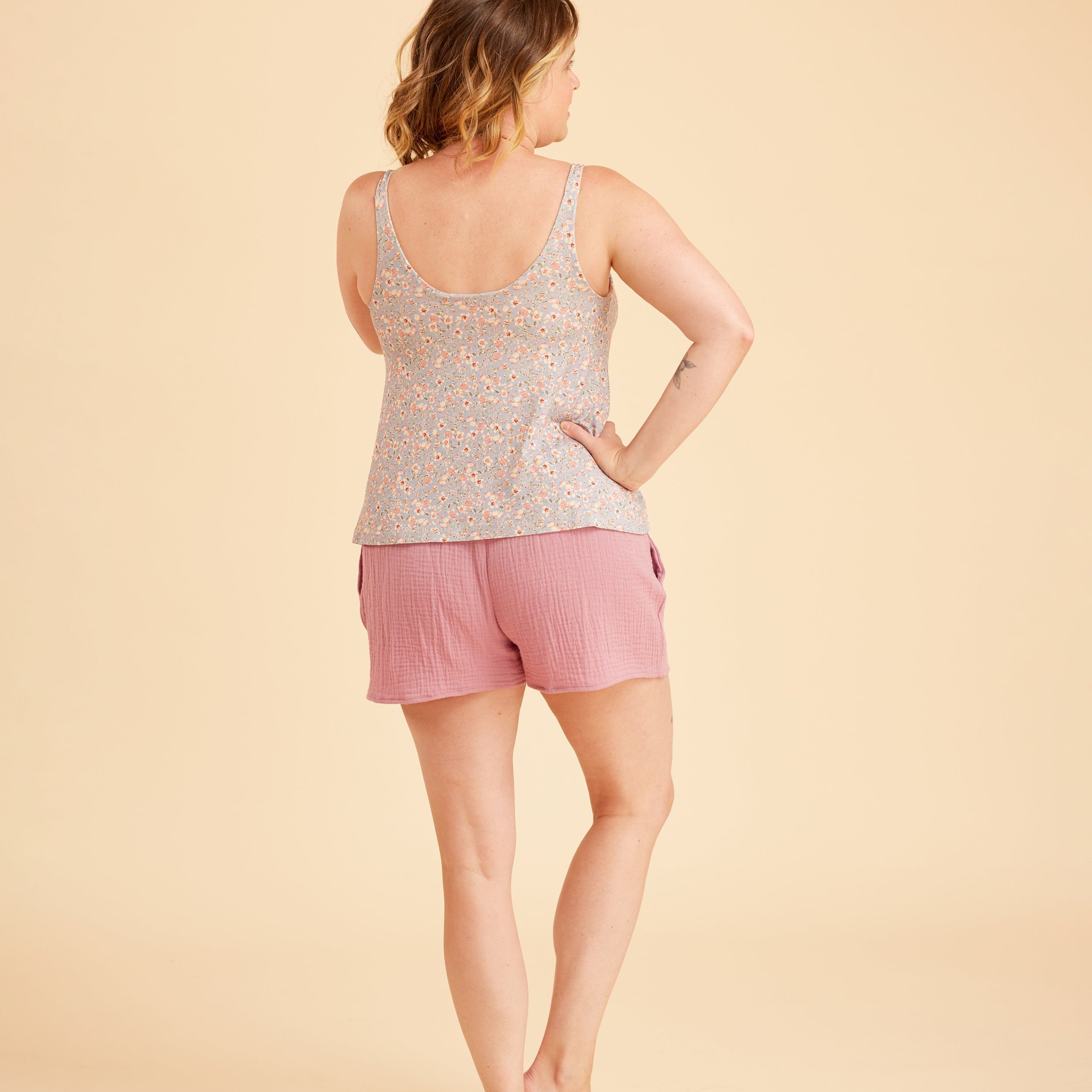 Woman wearing a patterned tank top and pink shorts on a beige background. This is the Fiske Sleepwear Set sewing pattern from Cashmerette.