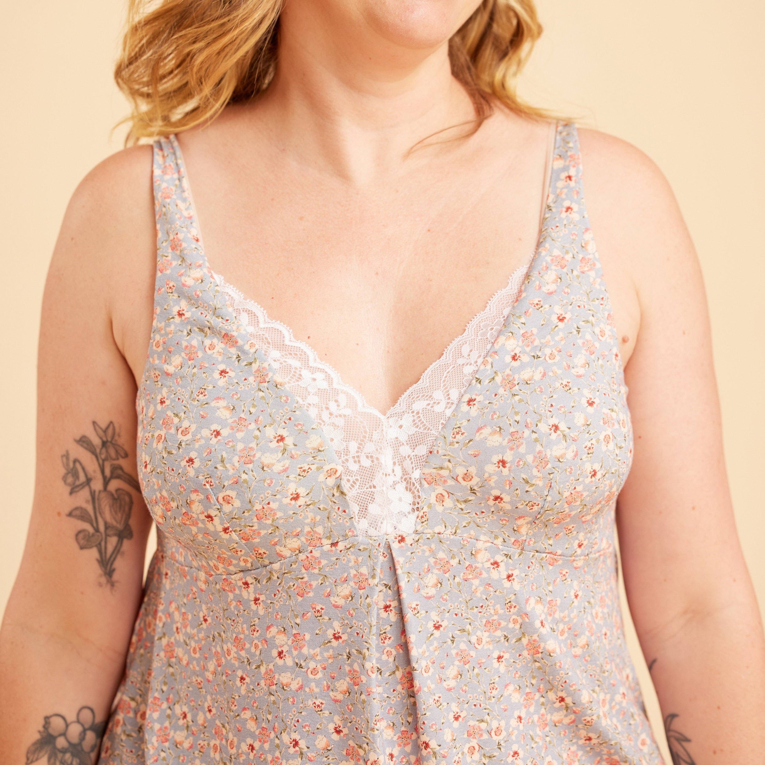 Woman wearing a floral sleeveless top against a beige background. This is the Fiske Sleepwear Set sewing pattern from Cashmerette.