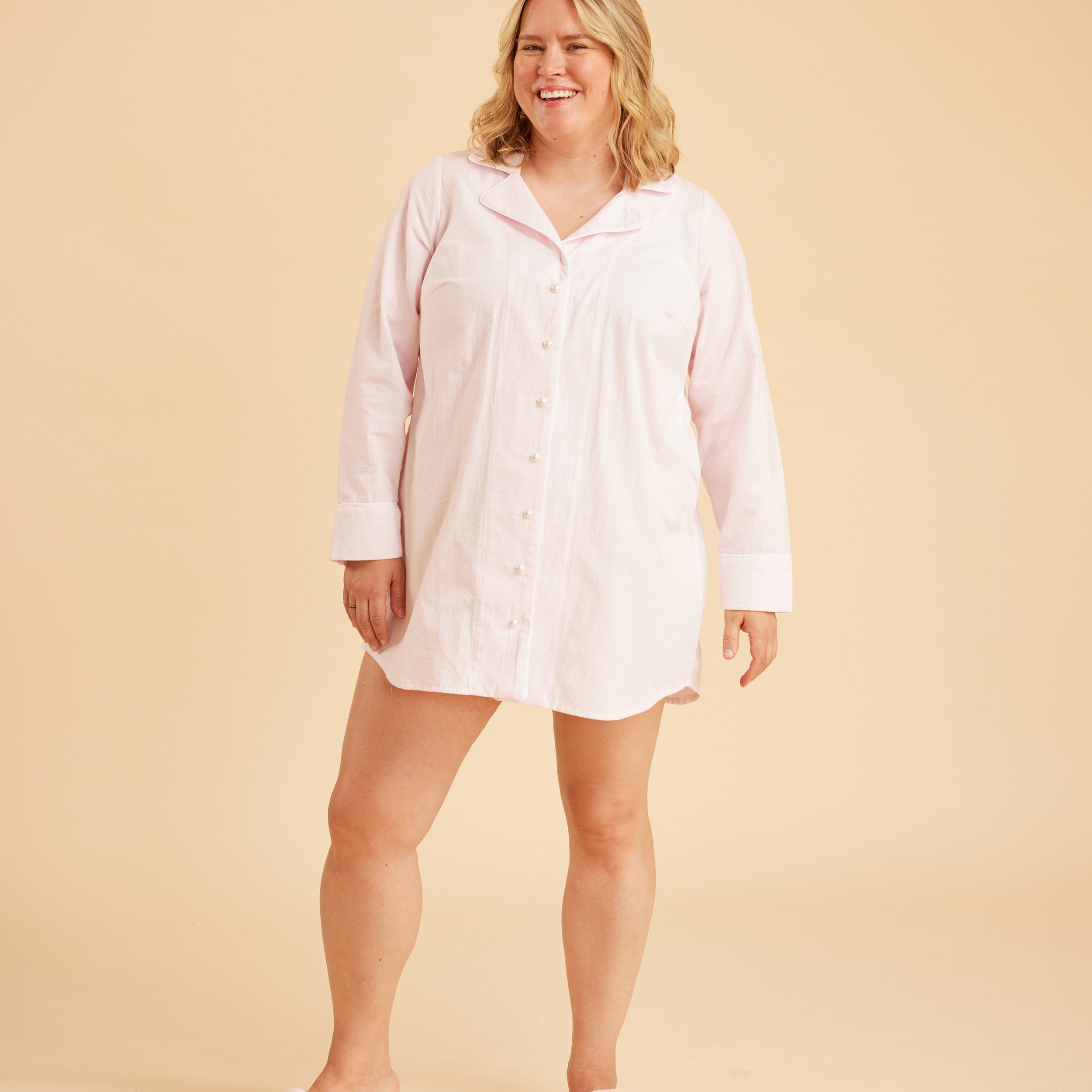 Woman wearing a light pink nightshirt on a beige background. This is the Fiske Sleepwear Set sewing pattern from Cashmerette.