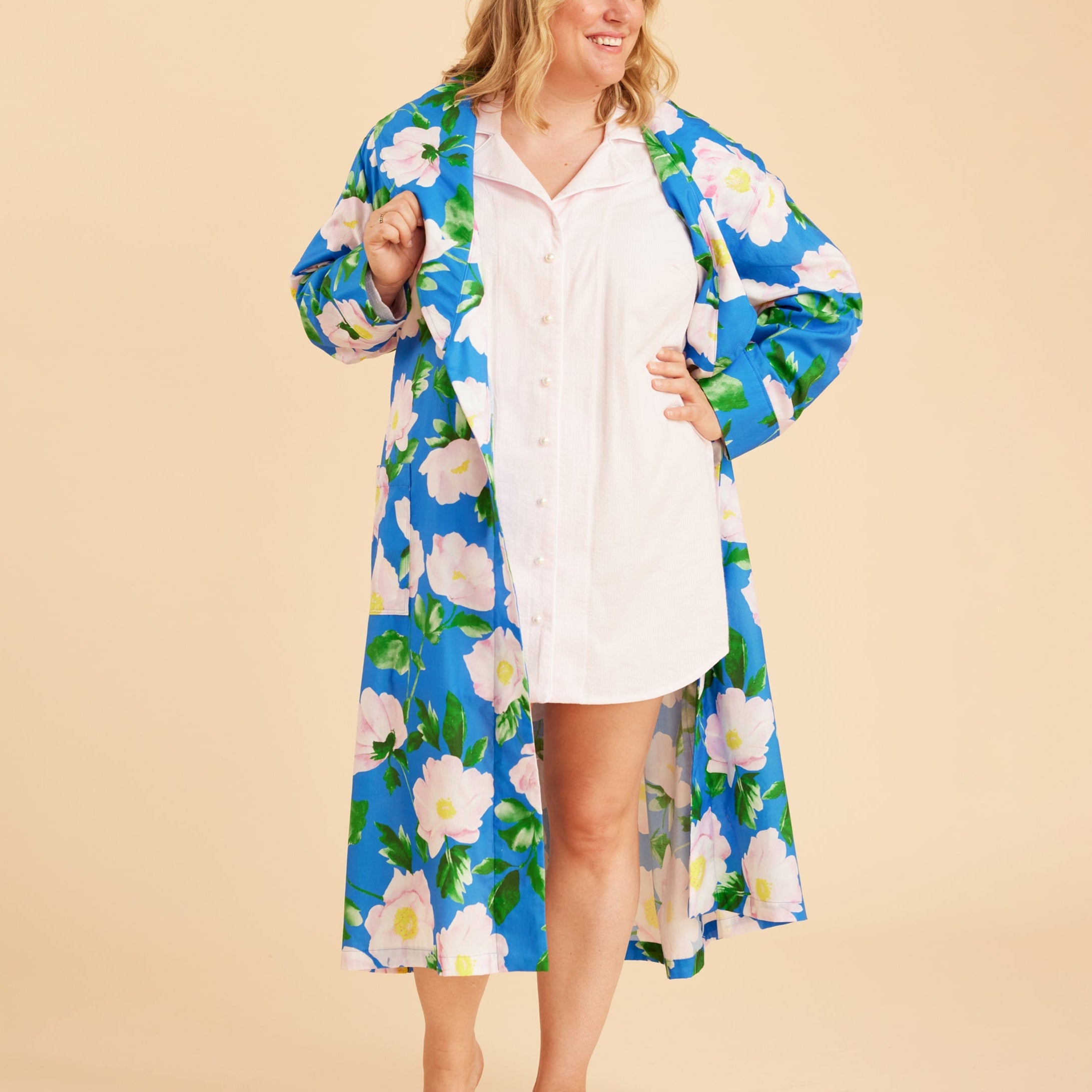 Woman wearing a blue floral robe over a white dress on a beige background. This is the Fiske Sleepwear Set sewing pattern from Cashmerette.