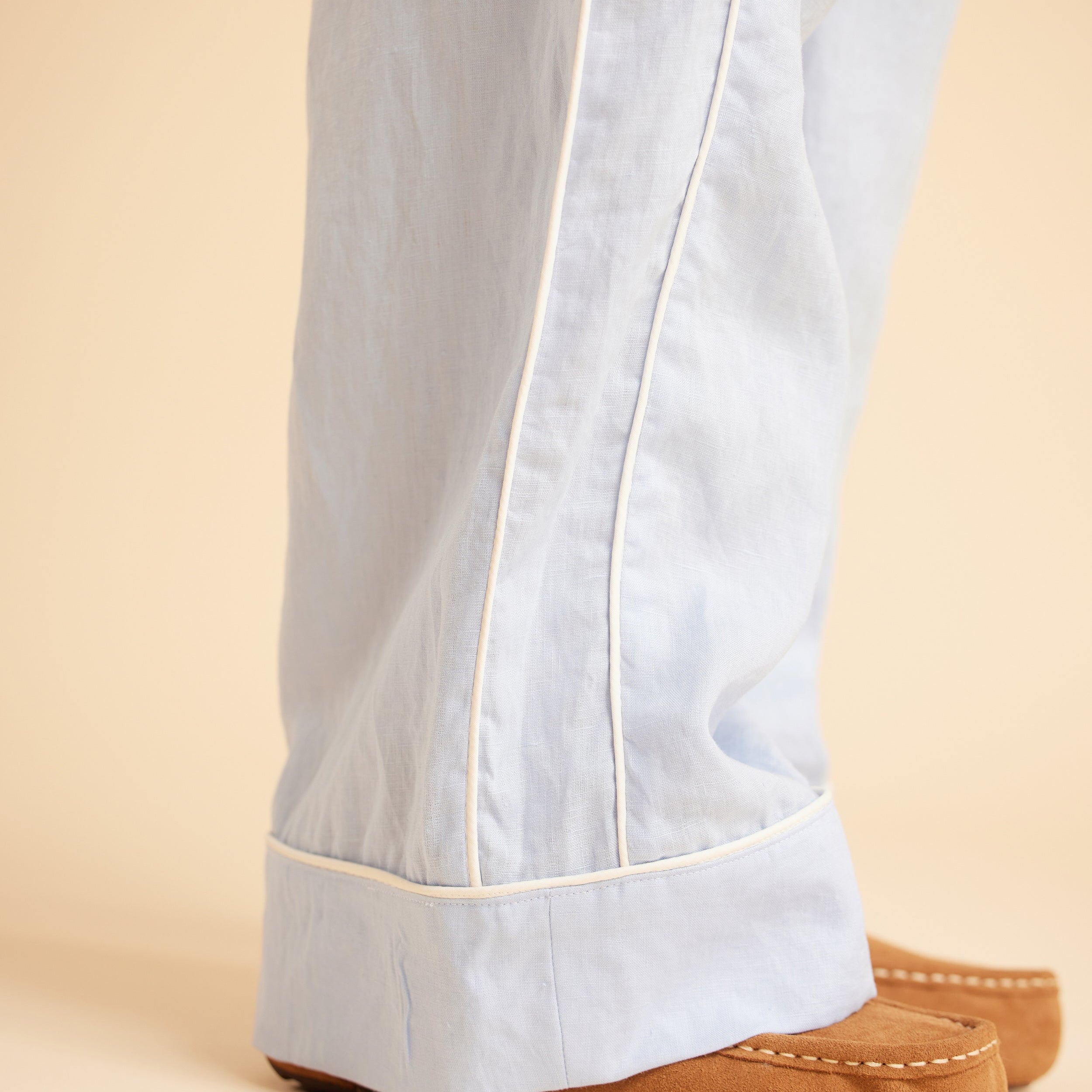 Light blue pants with white trim worn by a person on a beige background. This is the Fiske Sleepwear Set sewing pattern from Cashmerette.