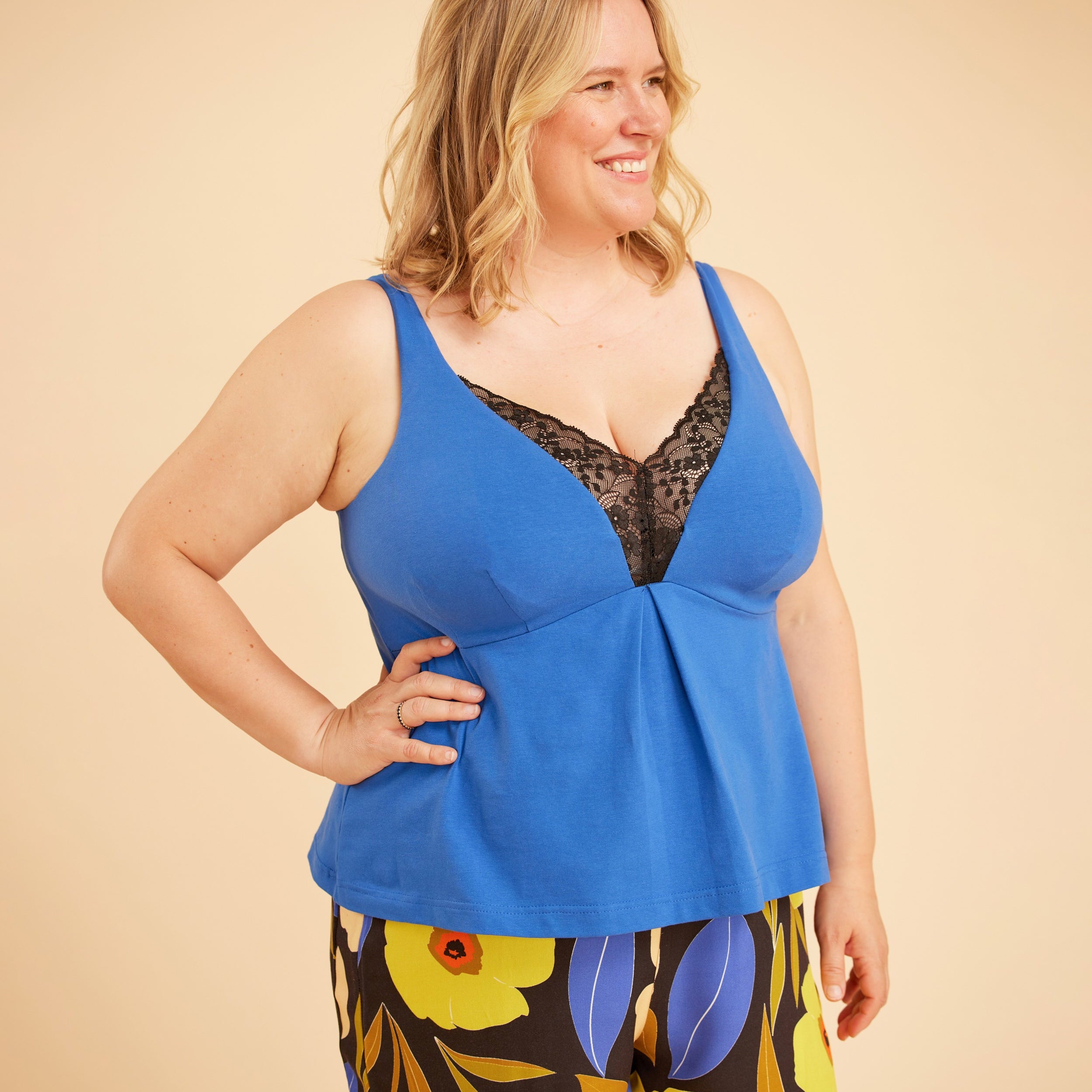 Woman wearing a blue top with floral pants on a beige background. This is the Fiske Sleepwear Set sewing pattern from Cashmerette.