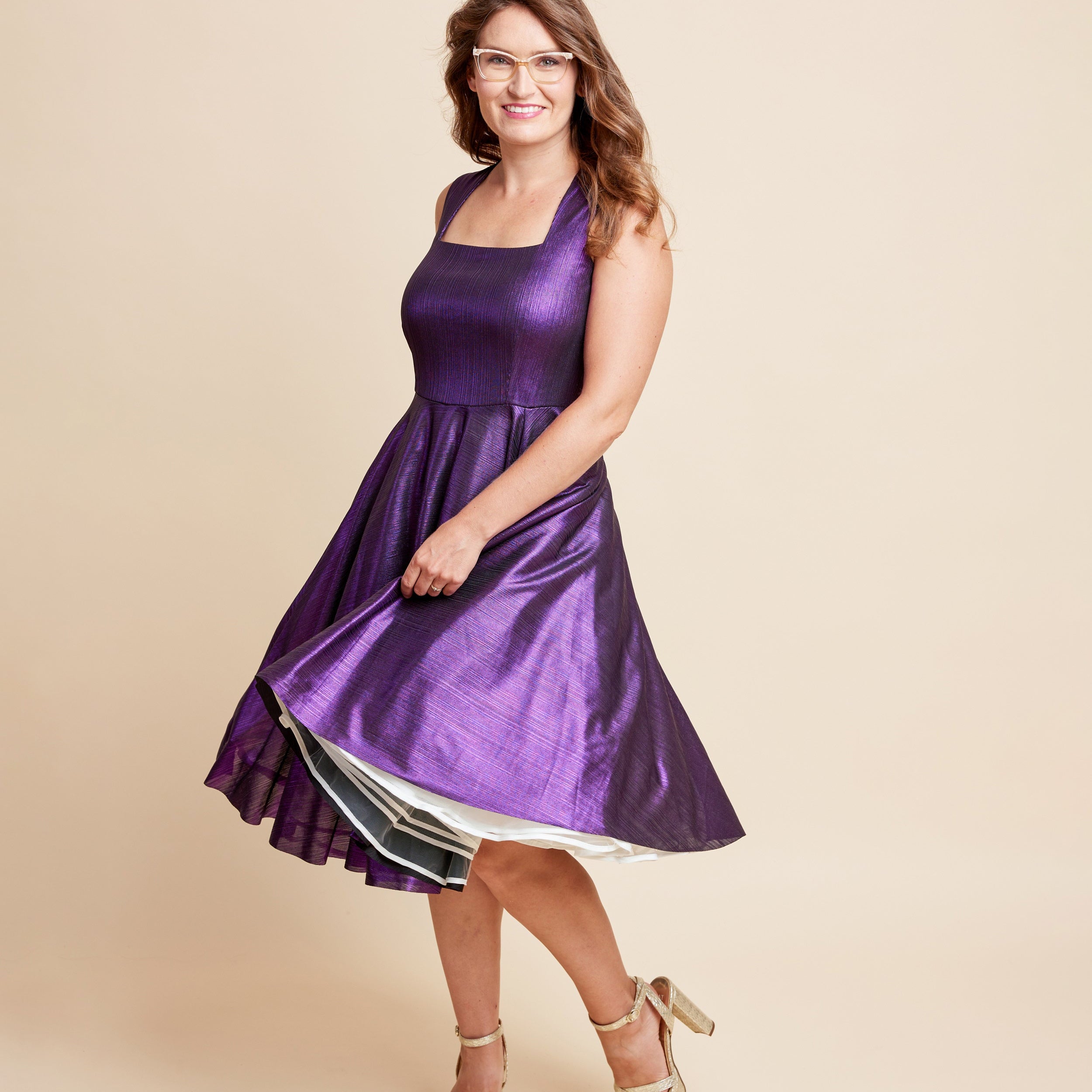 Woman wearing a purple dress on a beige background. This is the Grafton Dress, Top & Skirt sewing pattern from Cashmrette.