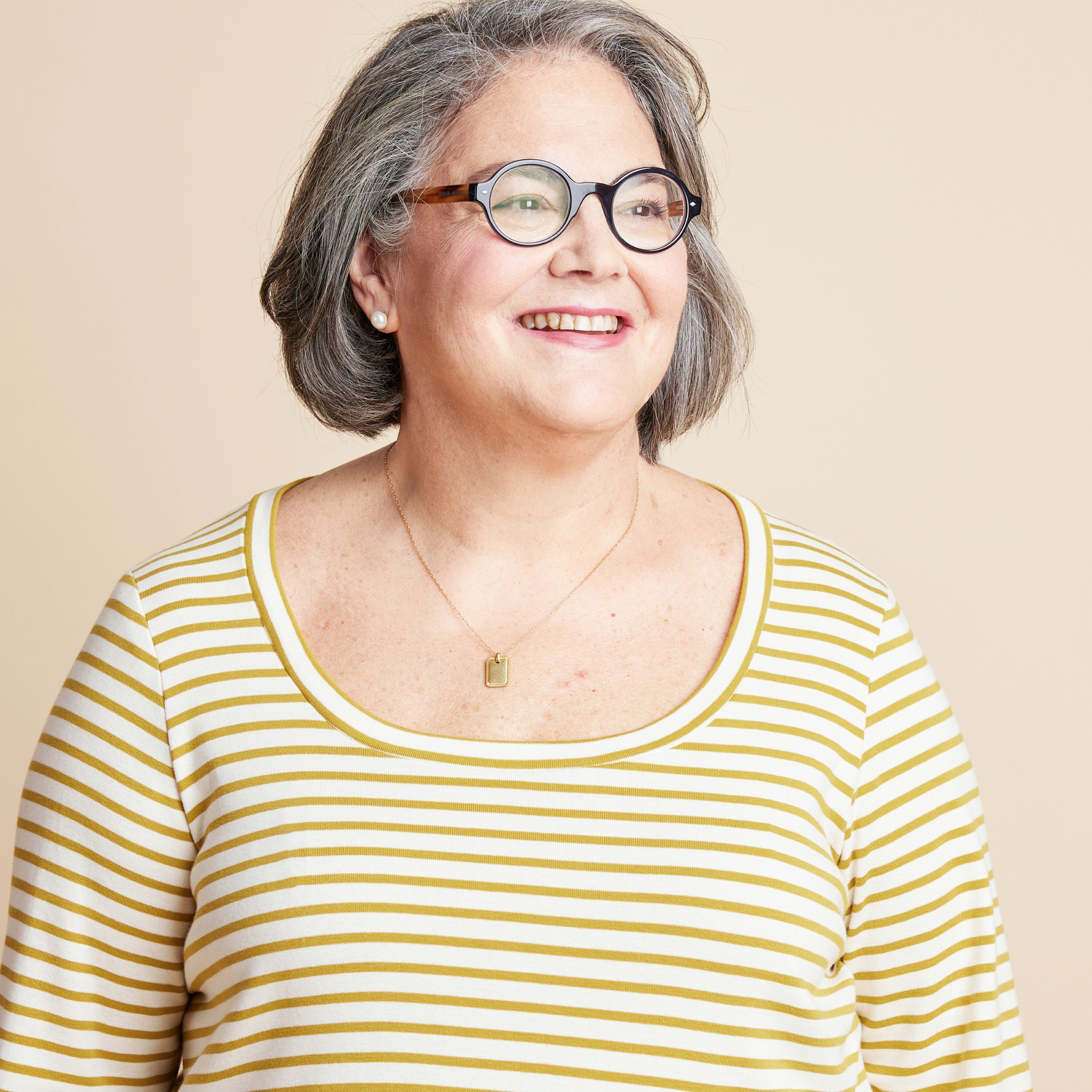 Woman wearing a yellow and white striped shirt against a beige background. This is the Grafton Dress, Top & Skirt sewing pattern from Cashmerette.