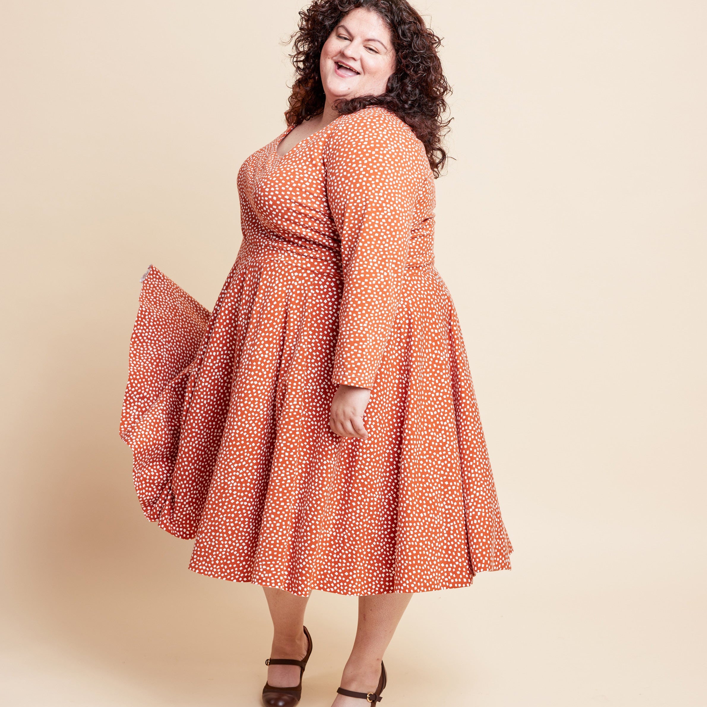 Woman wearing a red floral dress against a beige background. This is the Grafton Dress, Top & Skirt sewing pattern from Cashmerette.