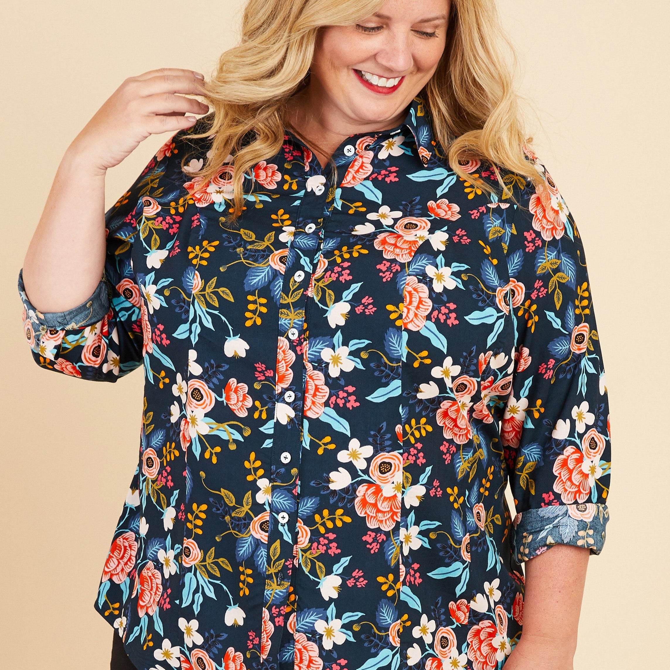 Woman wearing a floral blouse on a beige background. This button-up shirt is the Harrison Shirt sewing pattern from Cashmerette.
