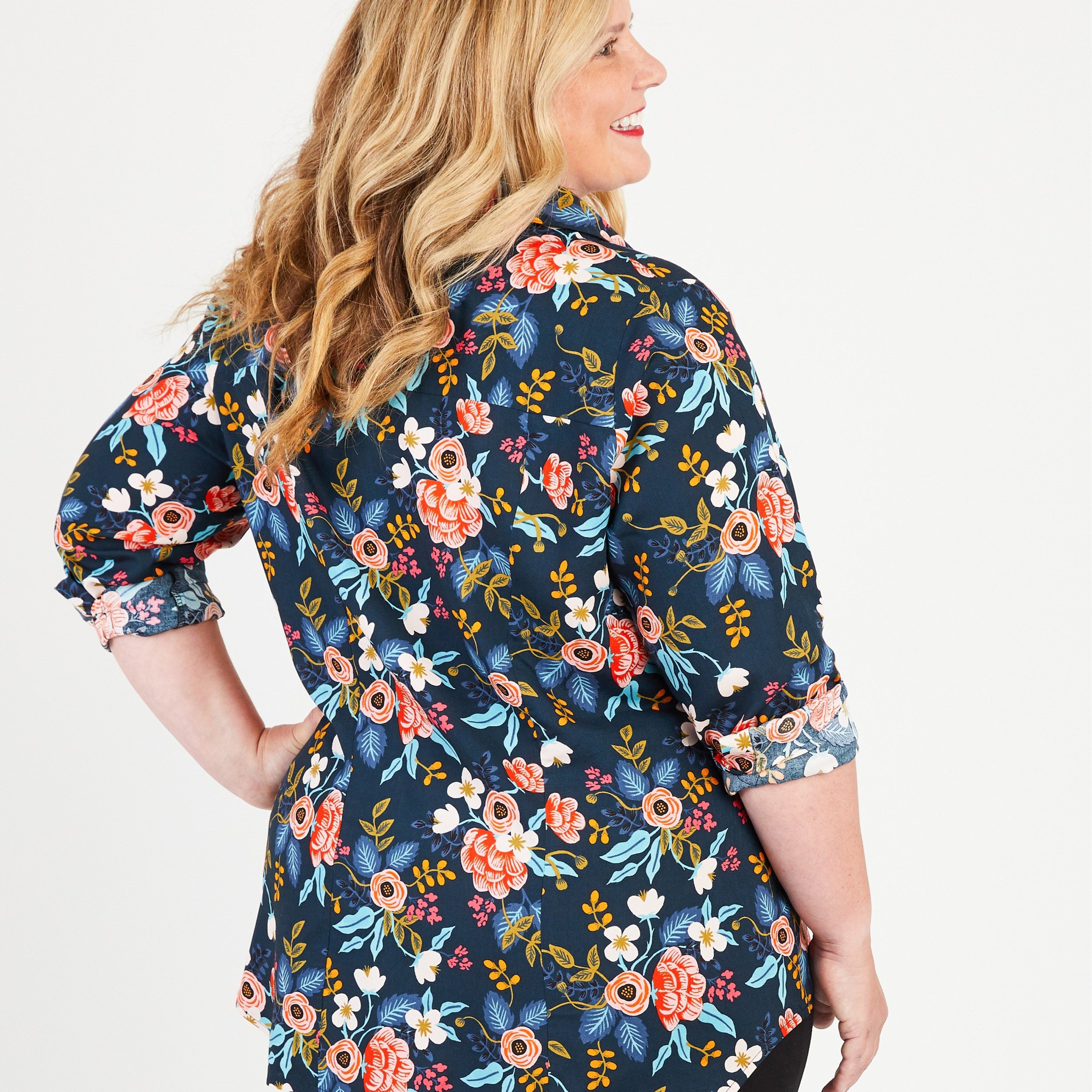 Woman wearing a navy floral blouse on a white background. This button-up shirt is the Harrison Shirt sewing pattern from Cashmerette.