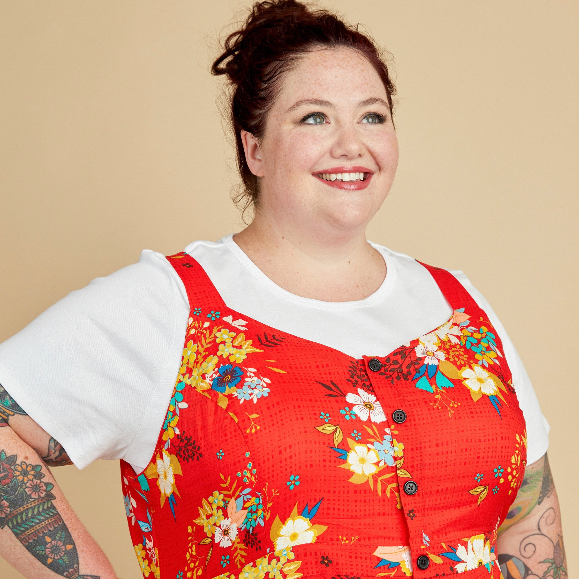 Woman wearing a red floral dress over a white shirt against a beige background. This is the Holyoke Maxi Dress & Skirt sewing pattern from Cashmerette.