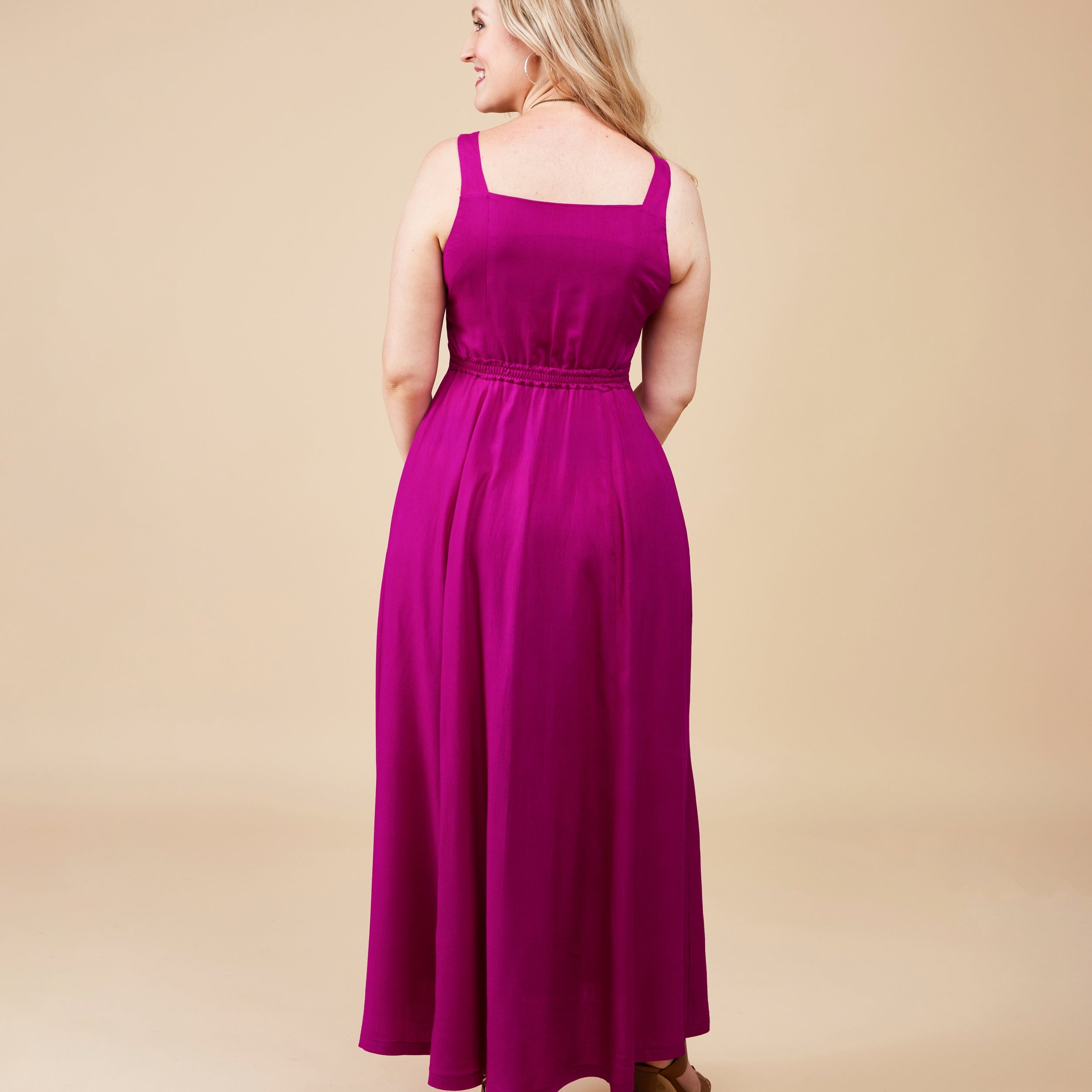Woman wearing a long magenta dress on a beige background. This is the Holyoke Maxi Dress & Skirt sewing pattern from Cashmerette.