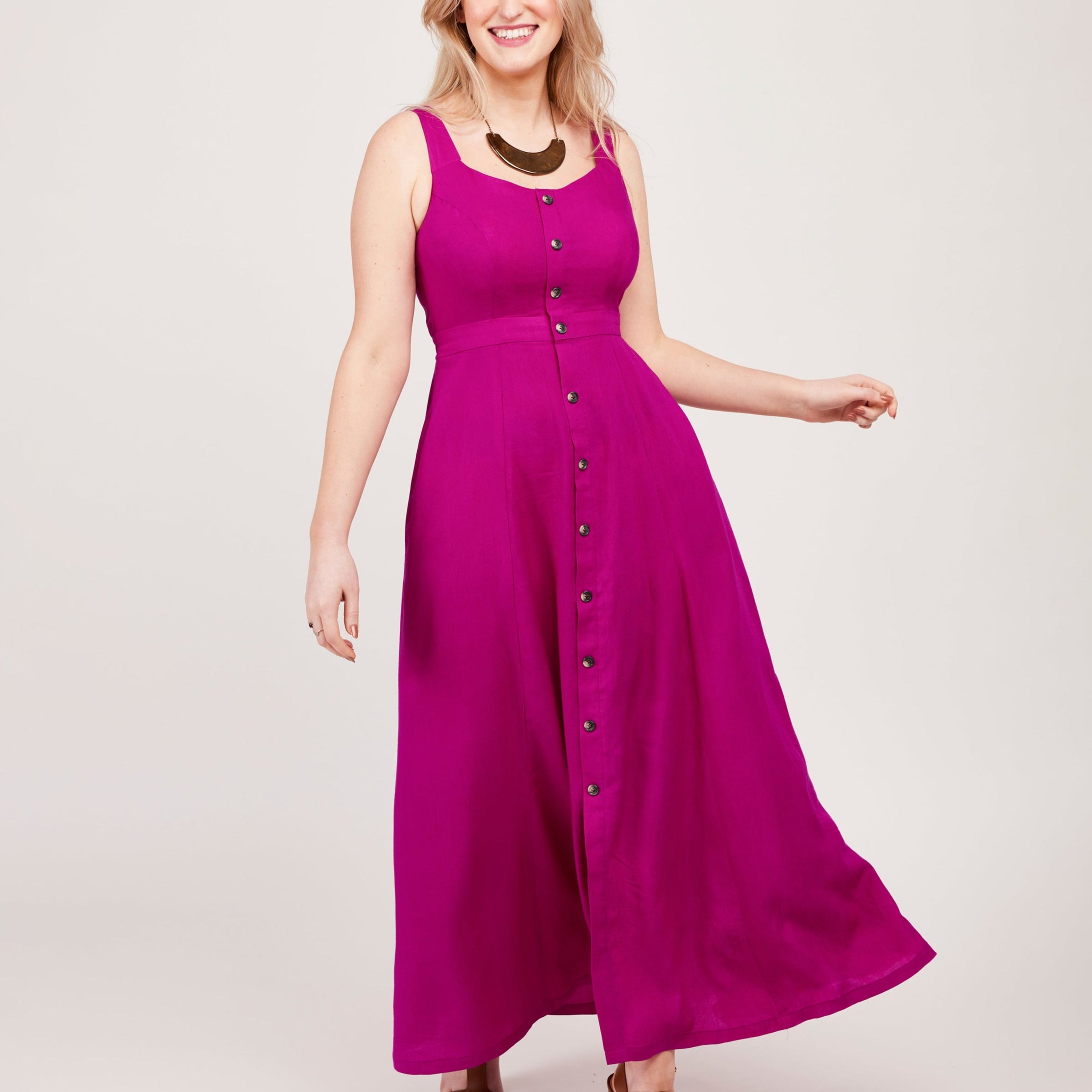 Woman wearing a pink dress with buttons on a white background. This is the Holyoke Maxi Dress & Skirt sewing pattern from Cashmerette.
