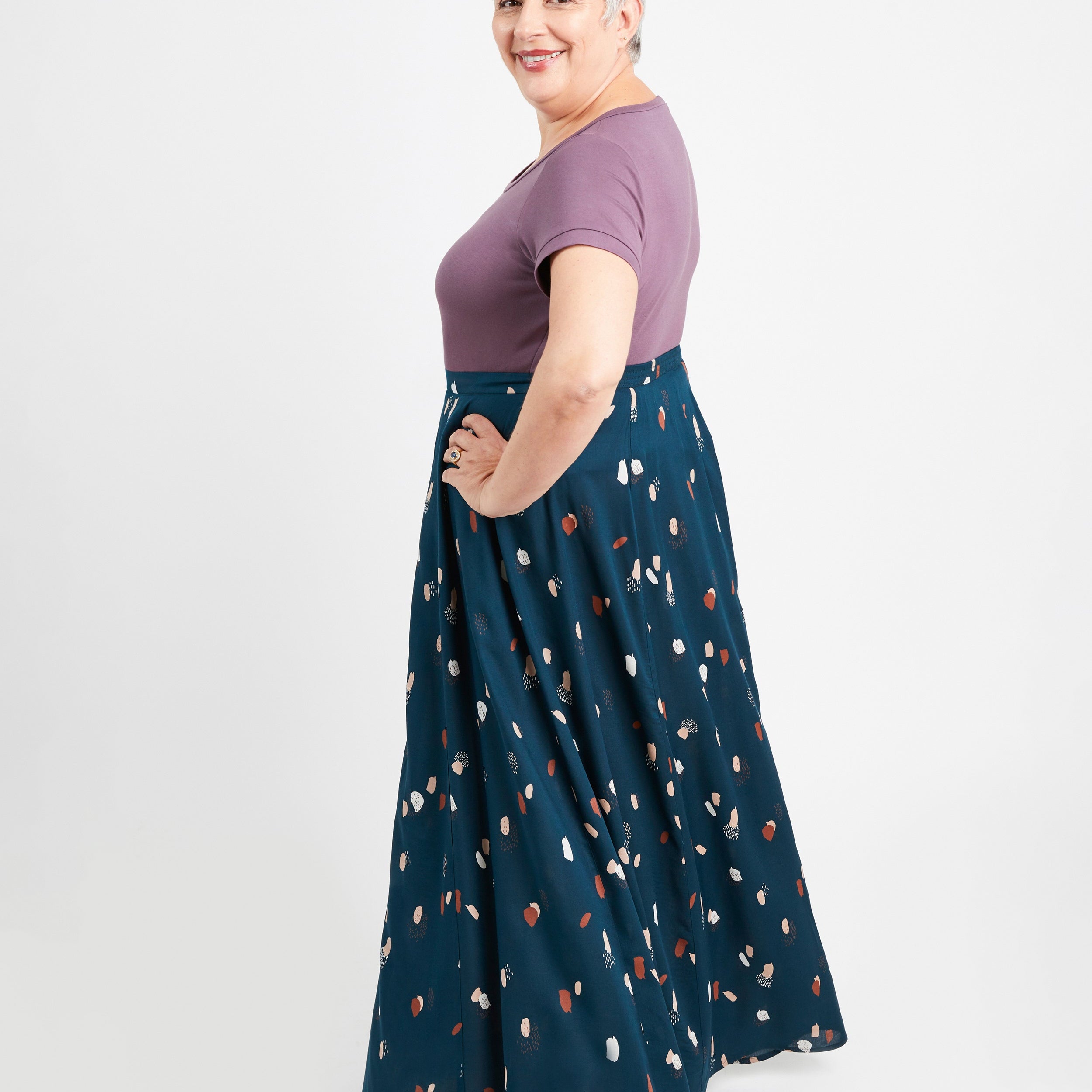 Woman wearing a purple top and blue skirt with a pattern on a white background. This is the Holyoke Maxi Dress & Skirt sewing pattern from Cashmerette.