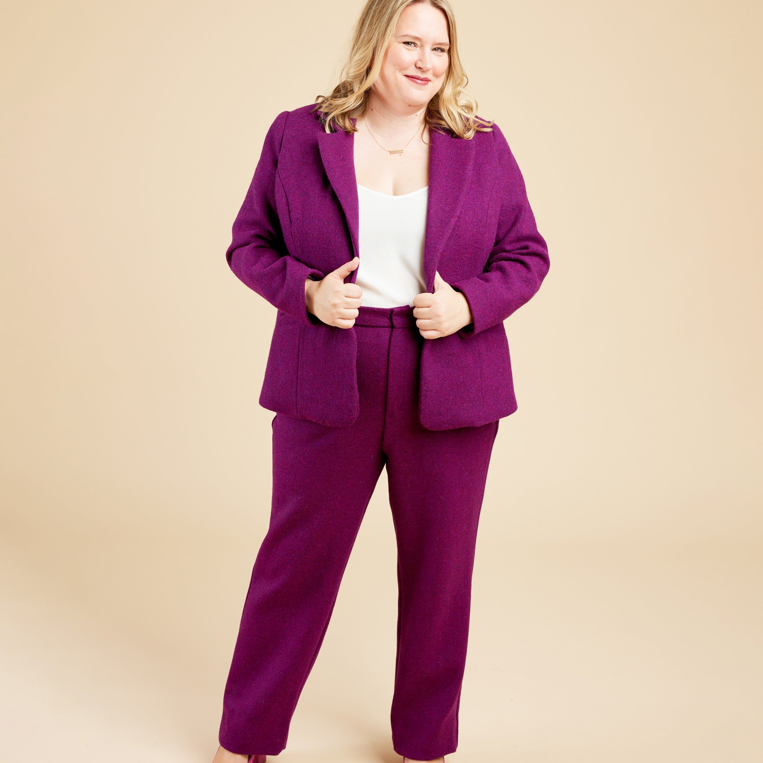 Woman wearing a purple suit on a beige background. These pants are the Meriam Trousers sewing pattern from Cashmerette.