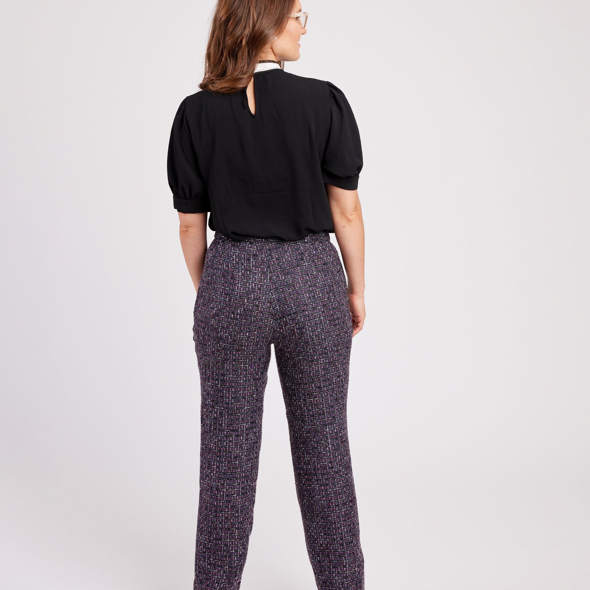 Woman wearing a black blouse and patterned pants on a white background. These pants are the Meriam Trousers sewing pattern from Cashmerette.