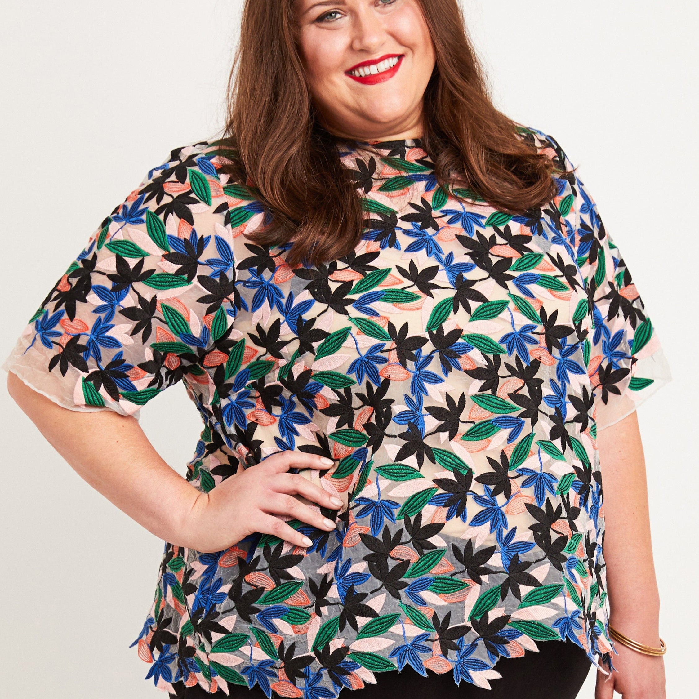Woman wearing a colorful floral blouse against a plain background. This top is the Montrose Top sewing pattern from Cashmerette.