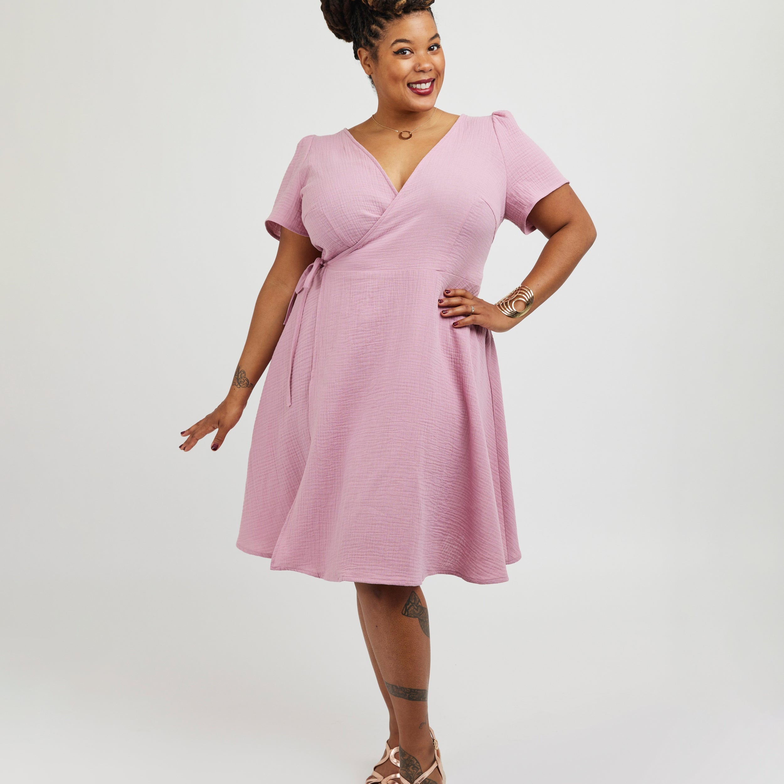 Woman wearing a pink dress against a white backgroundThis dress is the Roseclair Wrap Dress sewing pattern from Cashmerette.