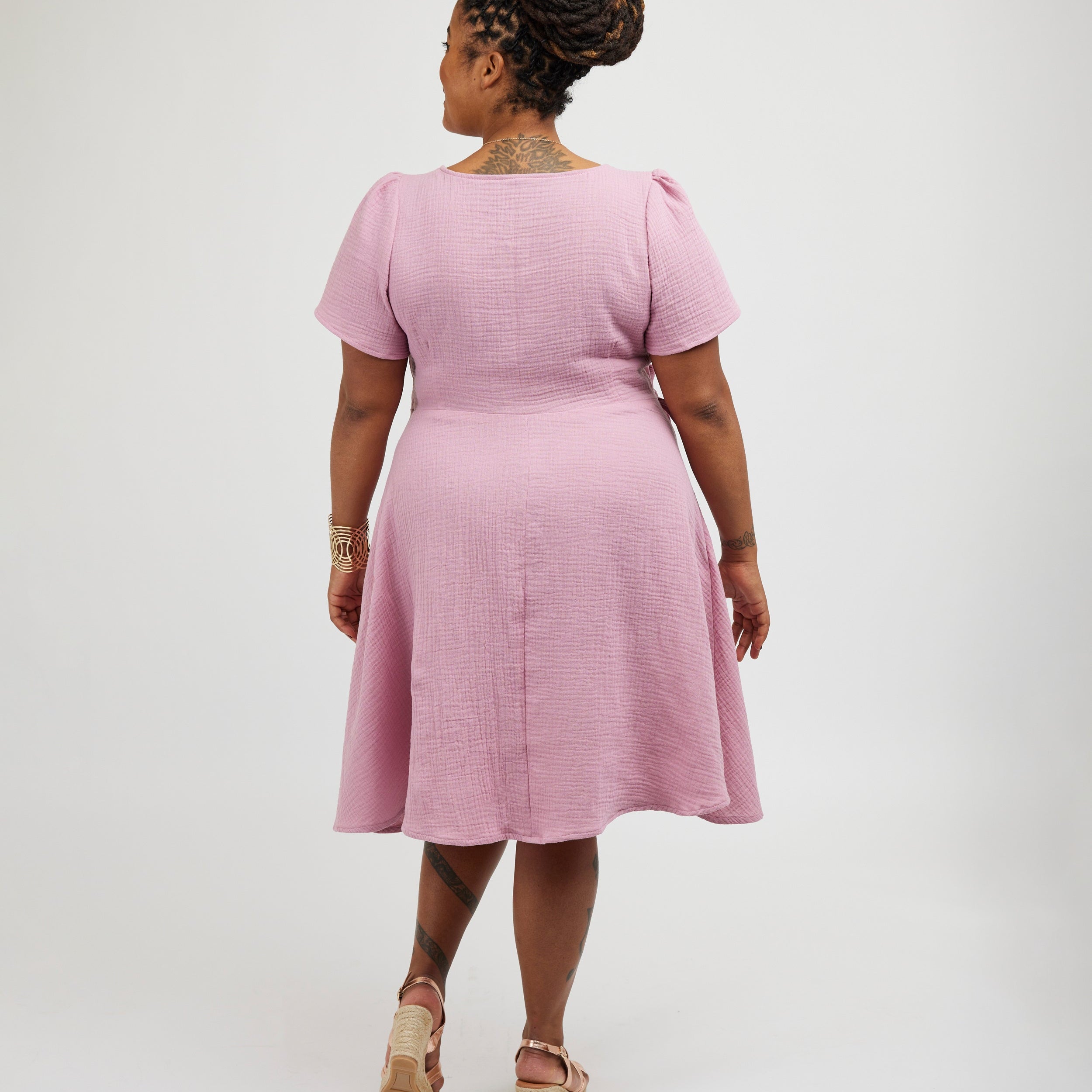 Woman wearing a pink dress on a white background. This dress is the Roseclair Wrap Dress sewing pattern from Cashmerette.