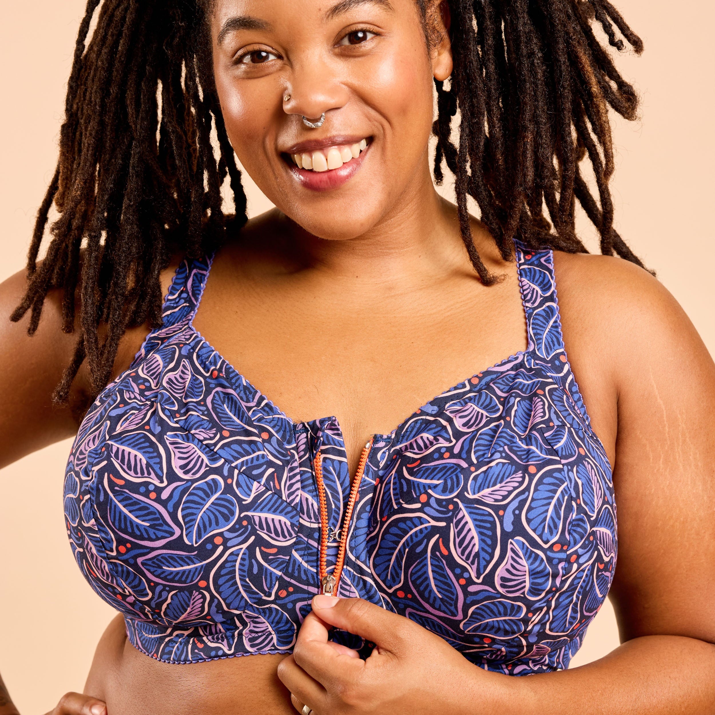Woman wearing a blue patterned bra against a beige background. This is the Cashmerette Somerville Sports Bra sewing pattern for big boobs.