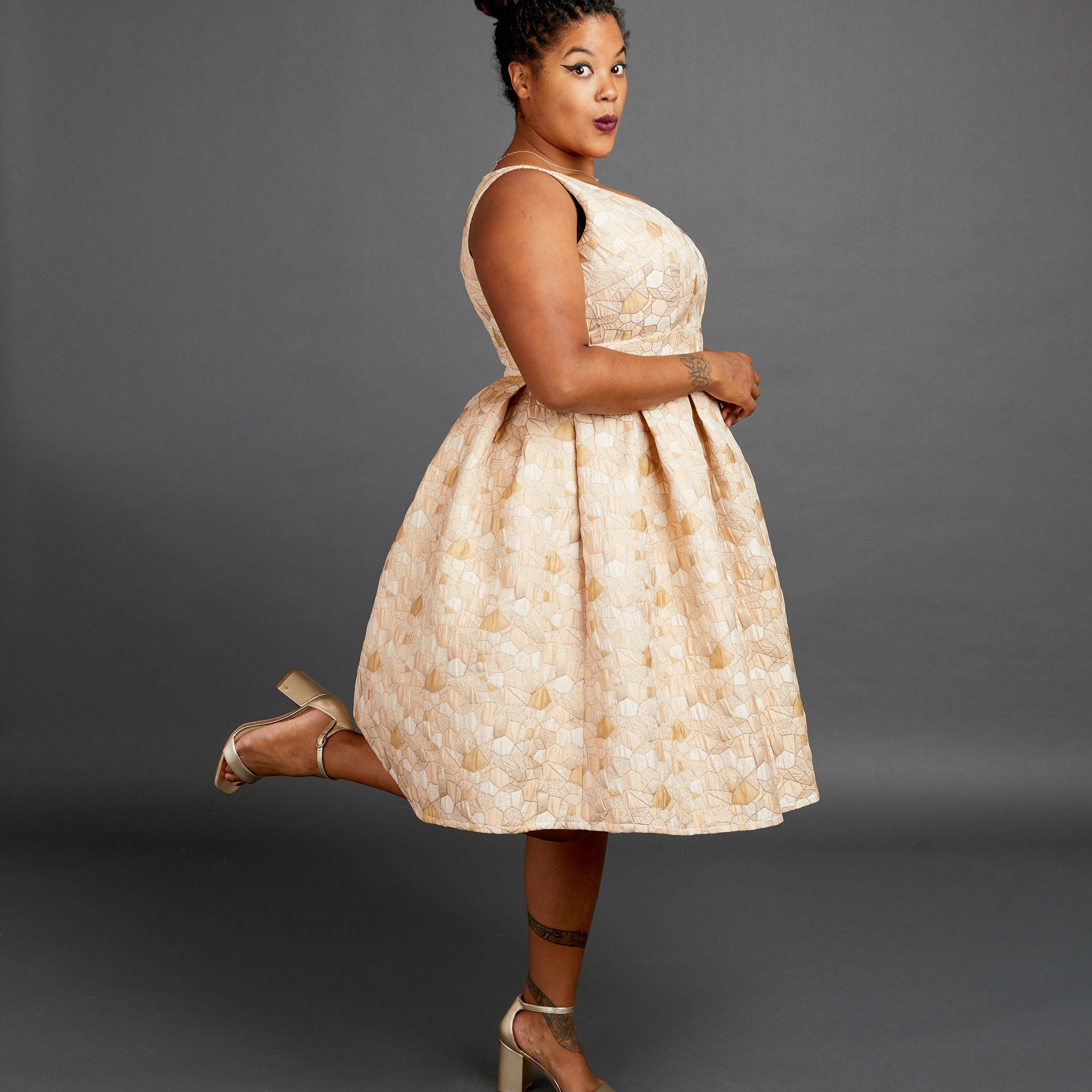 Woman wearing a beige patterned dress against a gray background. This dress is the Upton Dress & Skirt sewing pattern from Cashmerette.