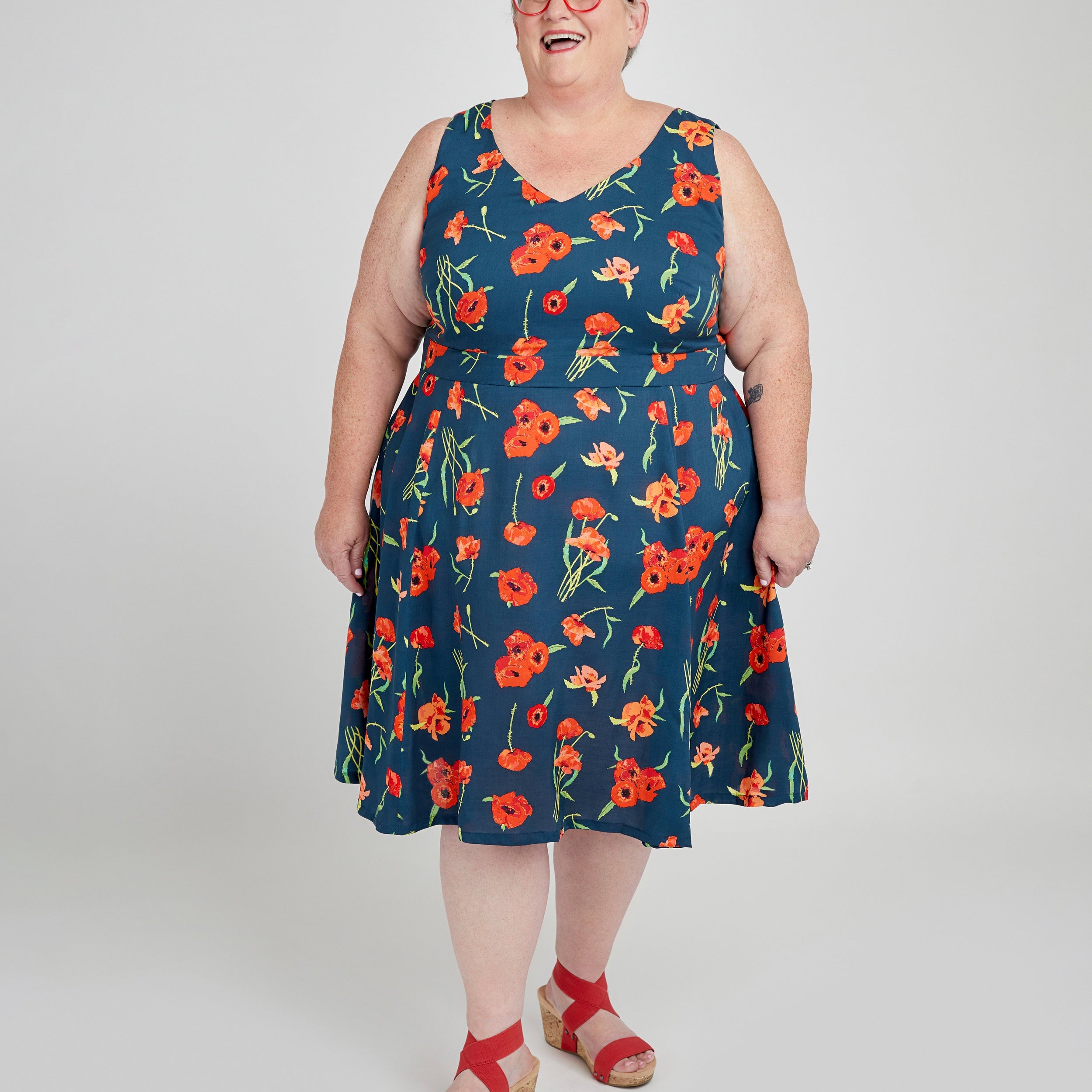 Woman wearing a blue dress with red floral pattern on a white background. This dress is the Upton Dress & Skirt sewing pattern from Cashmerette.