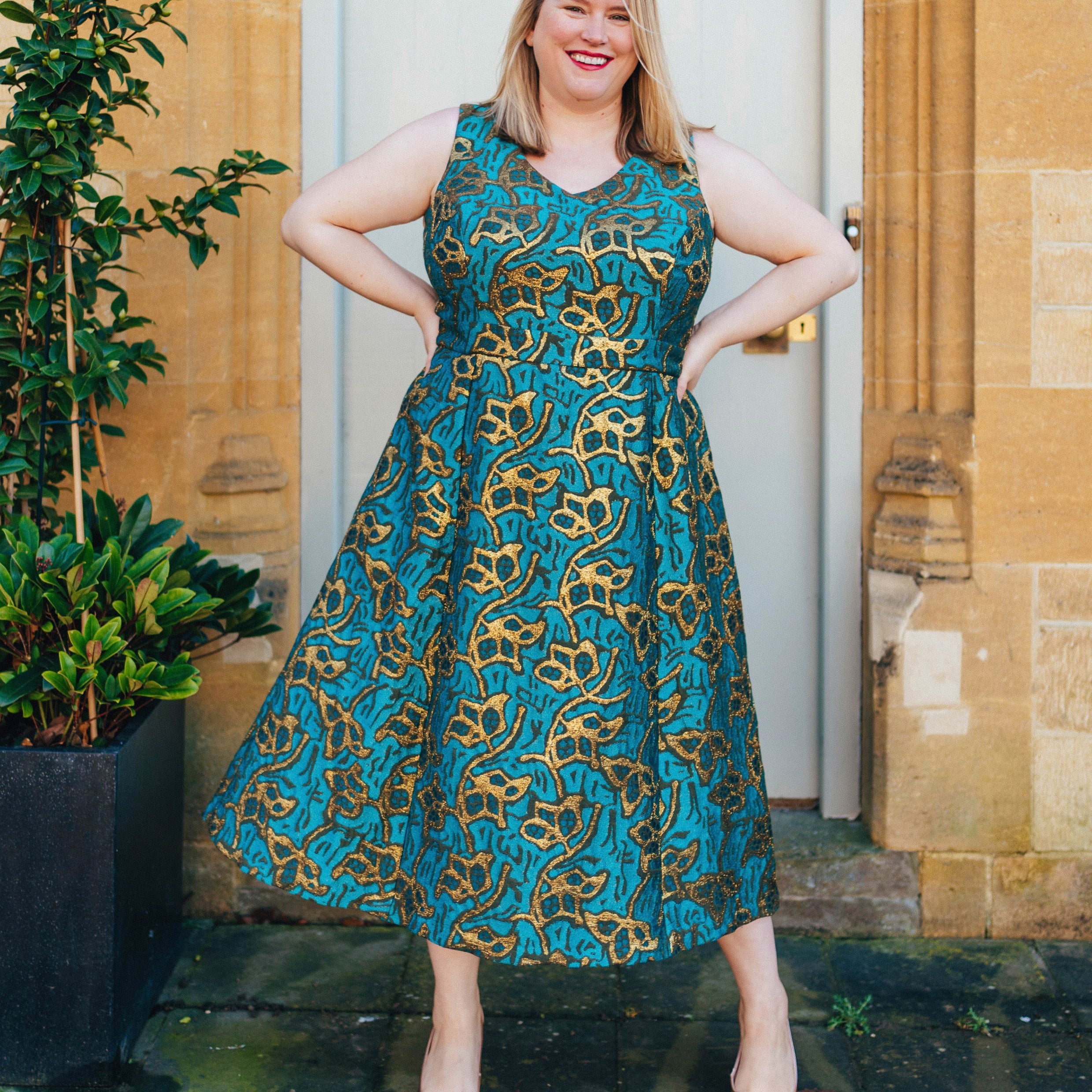 Woman wearing a blue and gold patterned dress standing outdoors. This dress is the Upton Dress & Skirt sewing pattern from Cashmerette.