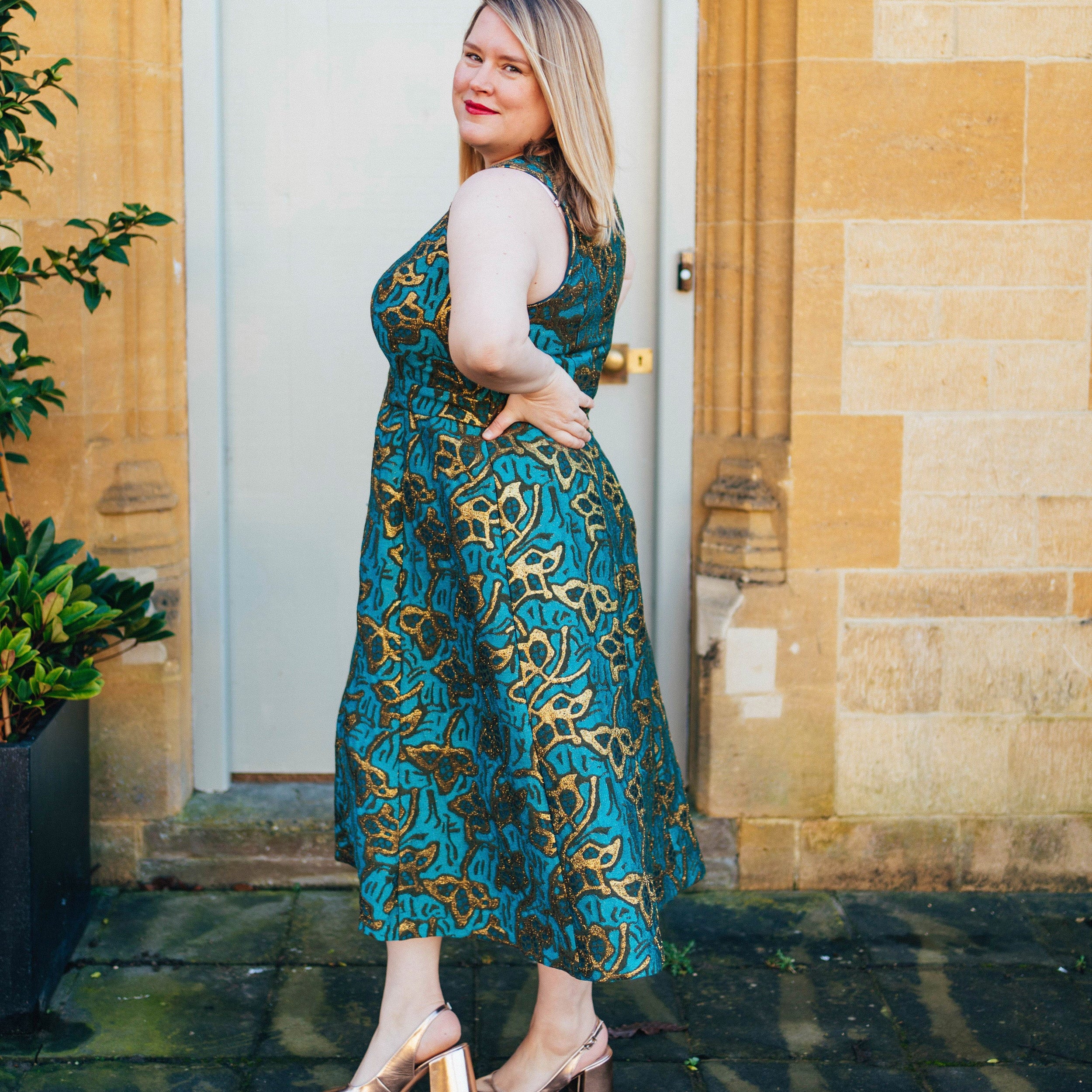 Woman in a teal patterned dress standing in front of a door.. This dress is the Upton Dress & Skirt sewing pattern from Cashmerette.