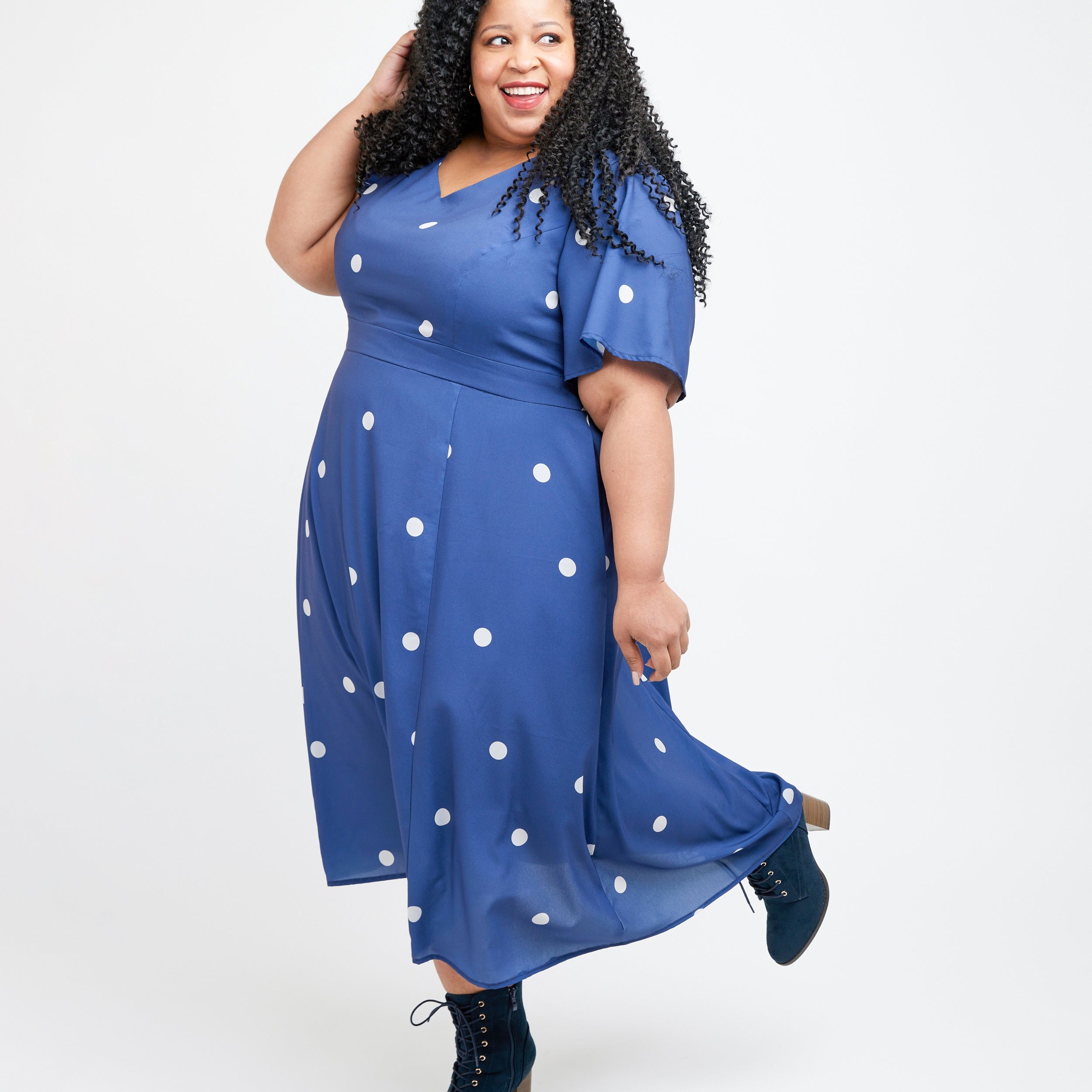 Woman wearing a blue dress with white polka dots on a white background. This dress is the Upton Dress & Skirt sewing pattern from Cashmerette.