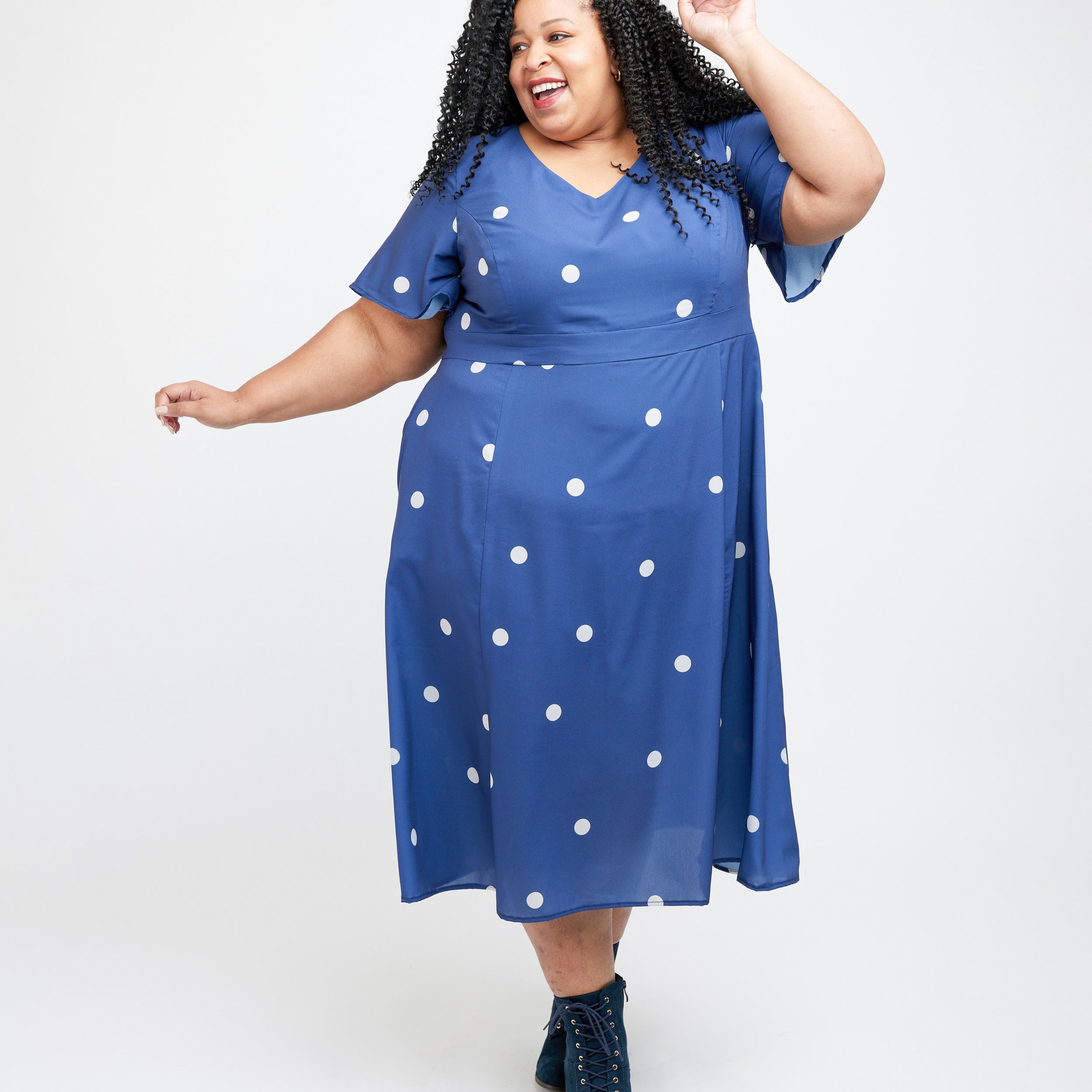 Woman wearing a blue dress with white polka dots on a white background. This dress is the Upton Dress & Skirt sewing pattern from Cashmerette.