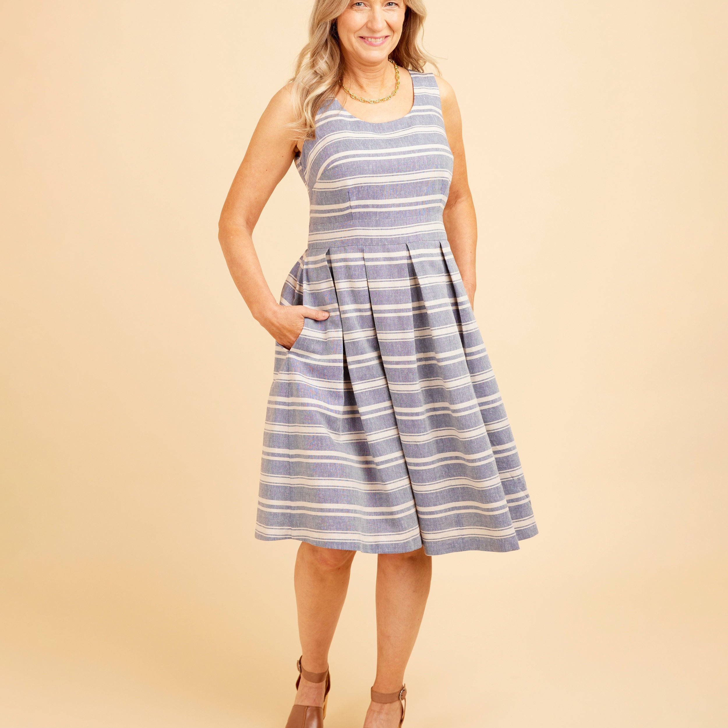Woman wearing a blue and white striped dress on a beige background. This dress is the Upton Dress & Skirt sewing pattern from Cashmerette.