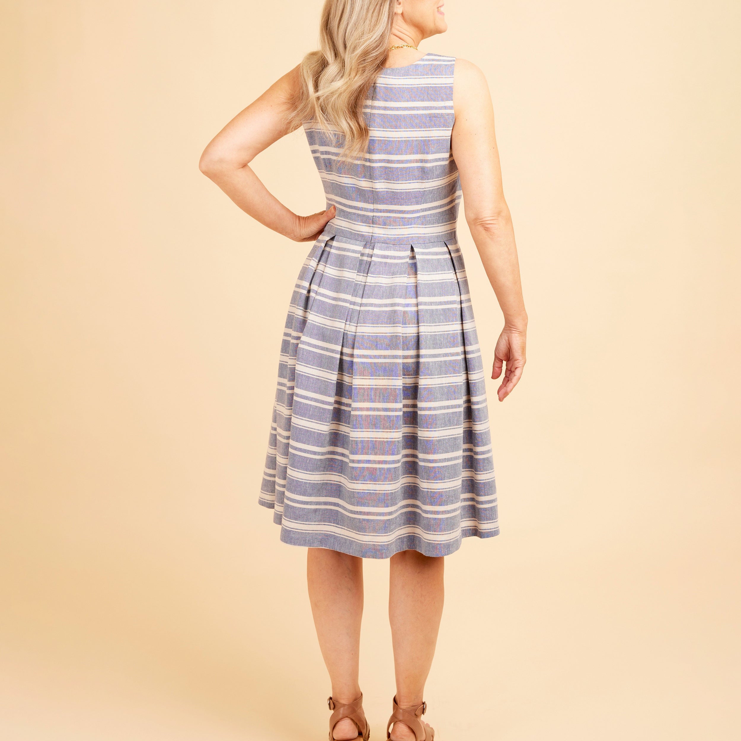 Woman wearing a blue and white striped dress against a beige background. This dress is the Upton Dress & Skirt sewing pattern from Cashmerette.