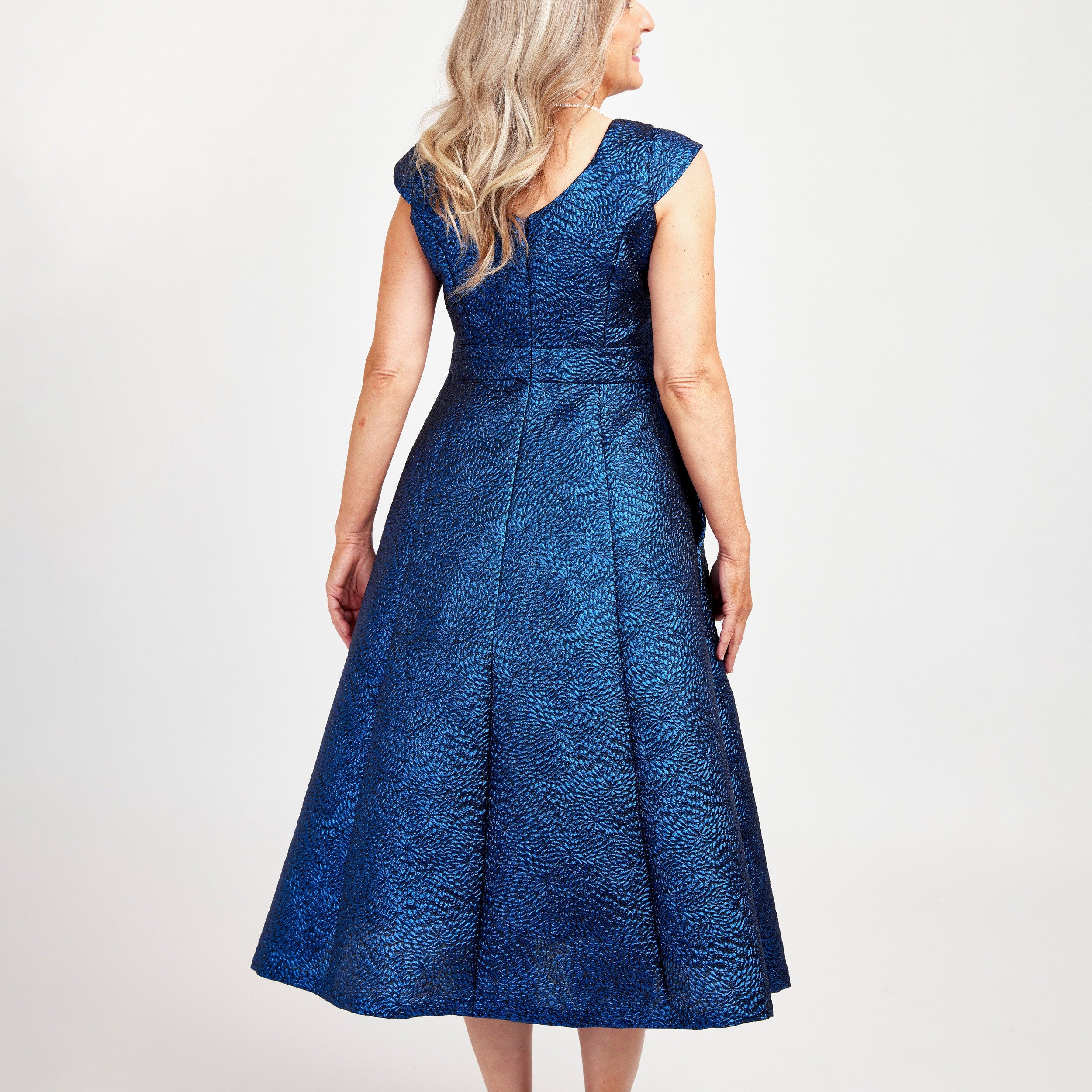 Woman wearing a blue lace dress on a white background. This dress is the Upton Dress & Skirt sewing pattern from Cashmerette.