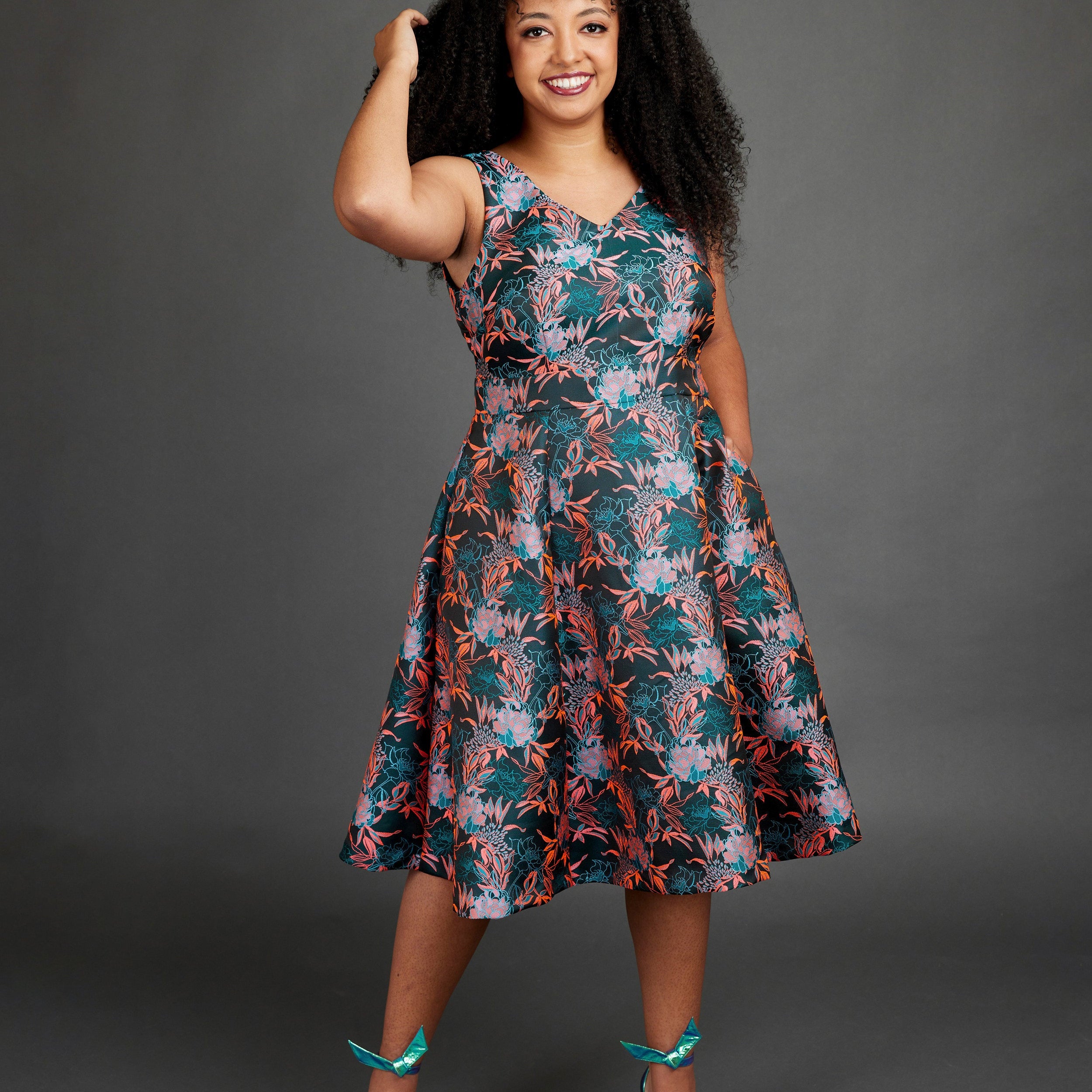 Woman wearing a floral dress against a gray background. This dress is the Upton Dress & Skirt sewing pattern from Cashmerette.