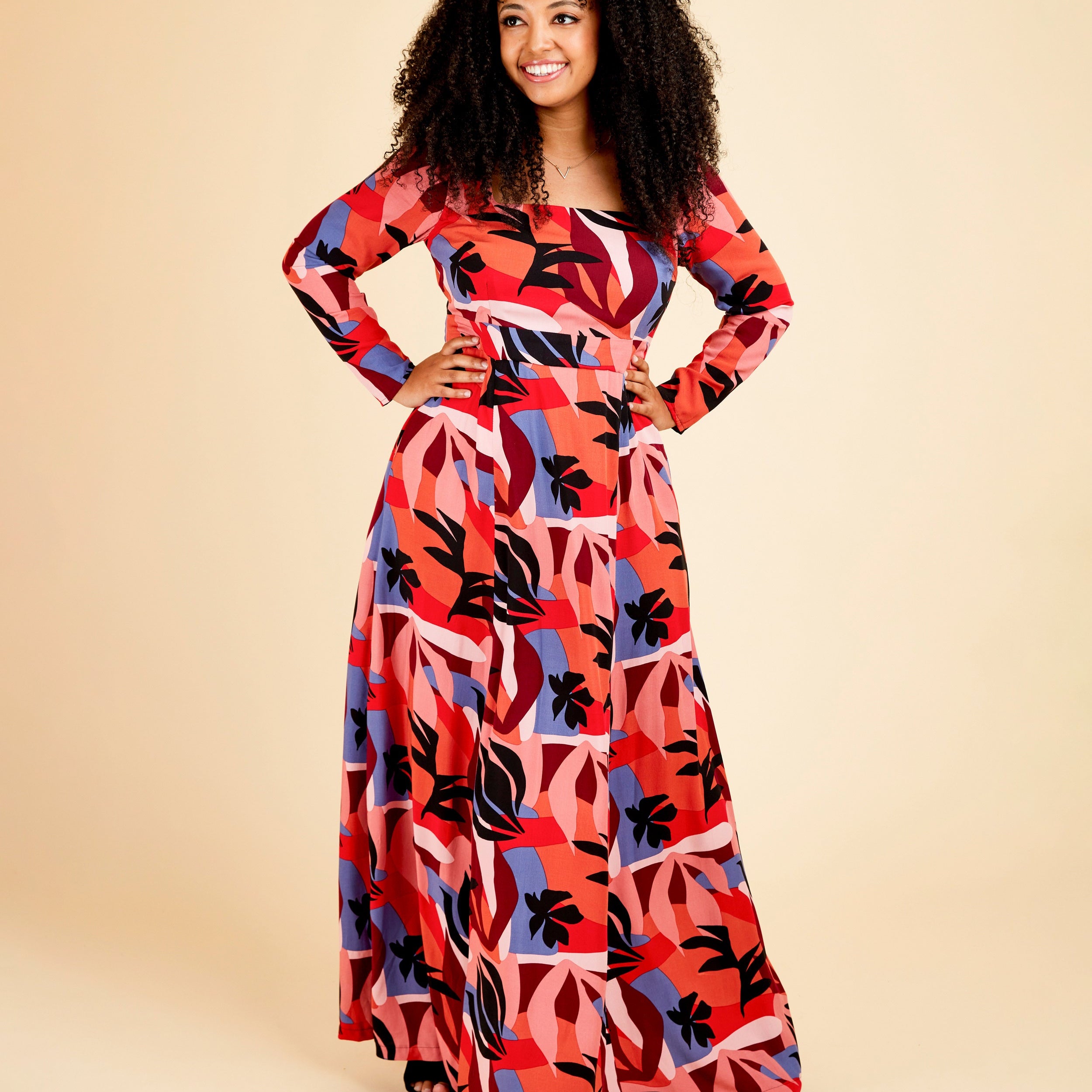 Woman wearing a colorful patterned dress on a beige background. This dress is the Upton Dress & Skirt sewing pattern from Cashmerette.