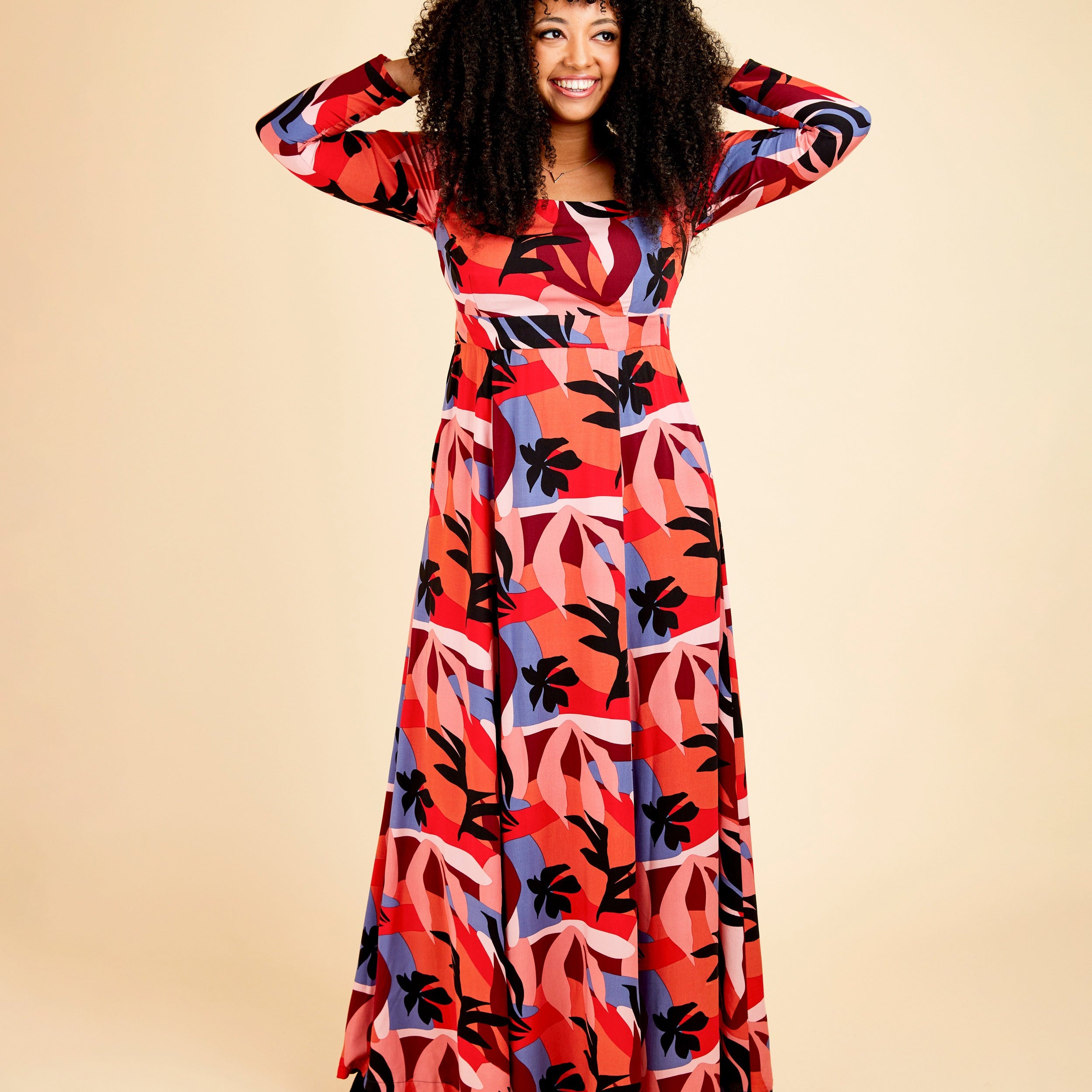 Woman wearing a colorful patterned dress on a beige background. This dress is the Upton Dress & Skirt sewing pattern from Cashmerette.
