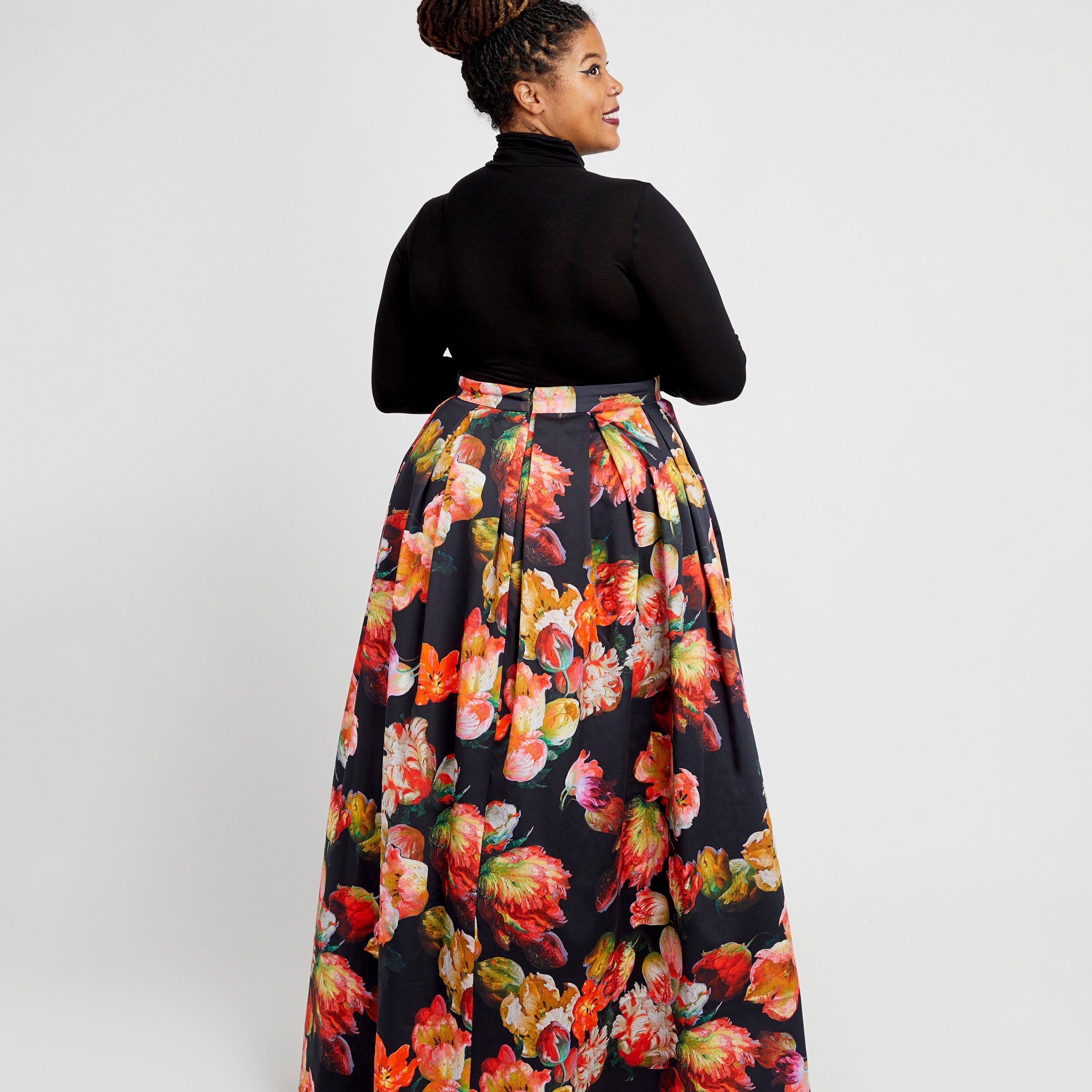Woman wearing a black turtleneck and floral skirt on a white background. This dress is the Upton Dress & Skirt sewing pattern from Cashmerette.
