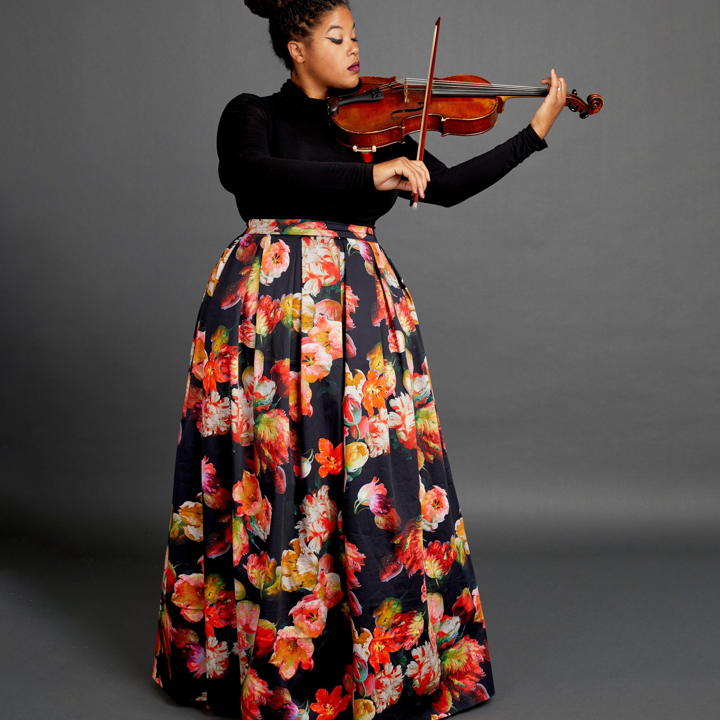 Person playing violin wearing a floral skirt on a gray background. This skirt is the Upton Dress & Skirt sewing pattern from Cashmerette.