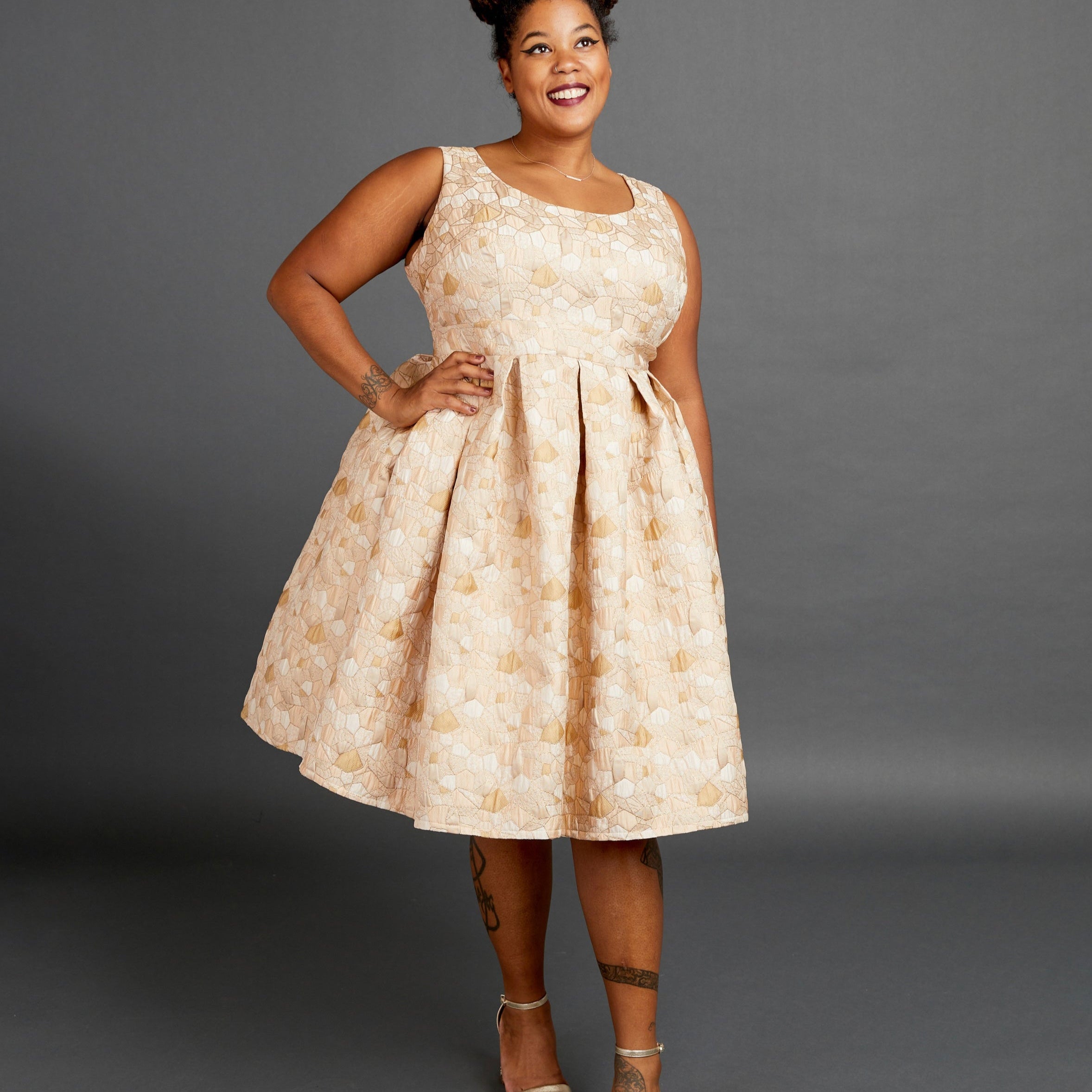 Woman wearing a beige floral dress against a gray background. This dress is the Upton Dress & Skirt sewing pattern from Cashmerette.