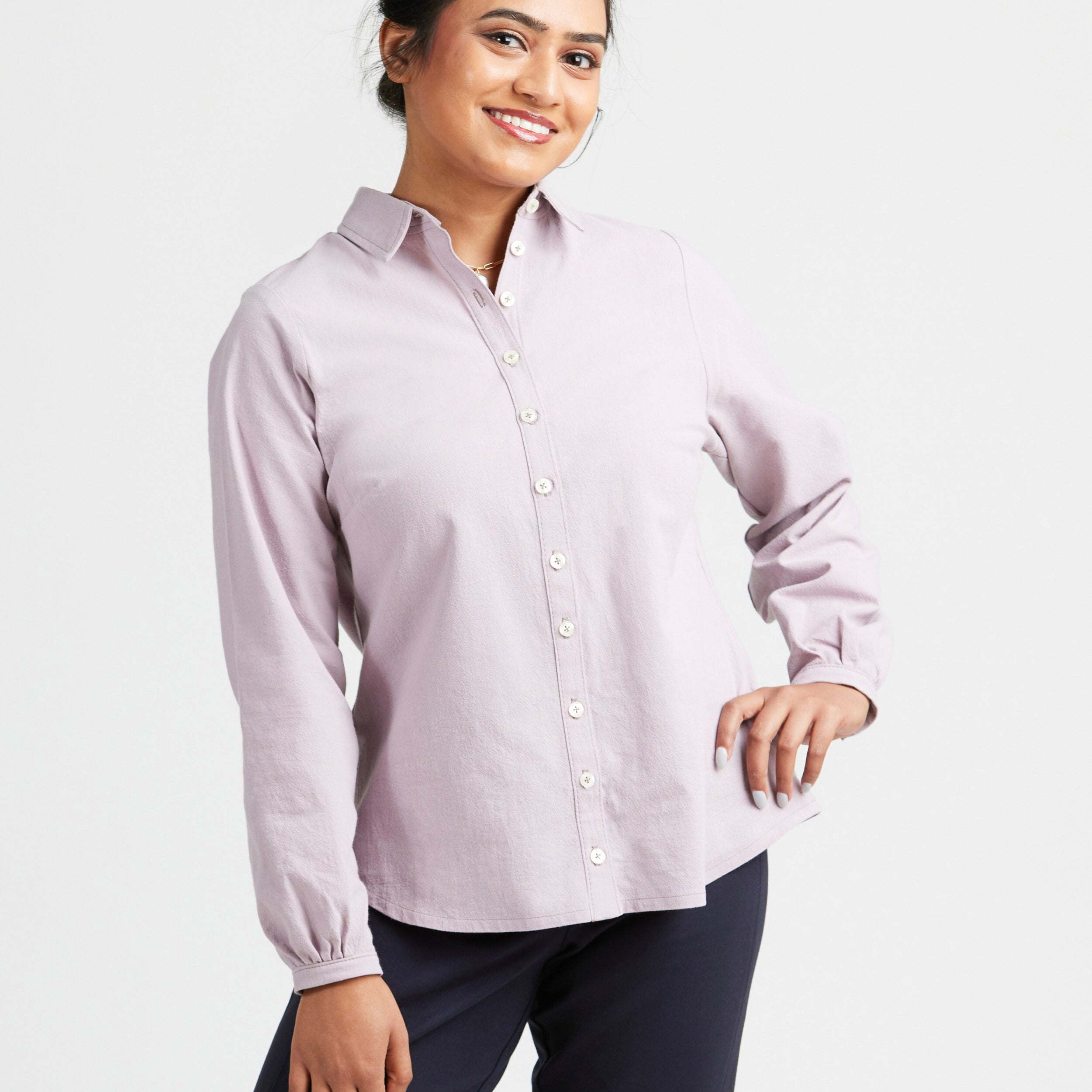 Woman wearing a light purple button-up shirt and dark pants on a white background. This top is the Vernon Shirt sewing pattern from Cashmerette.