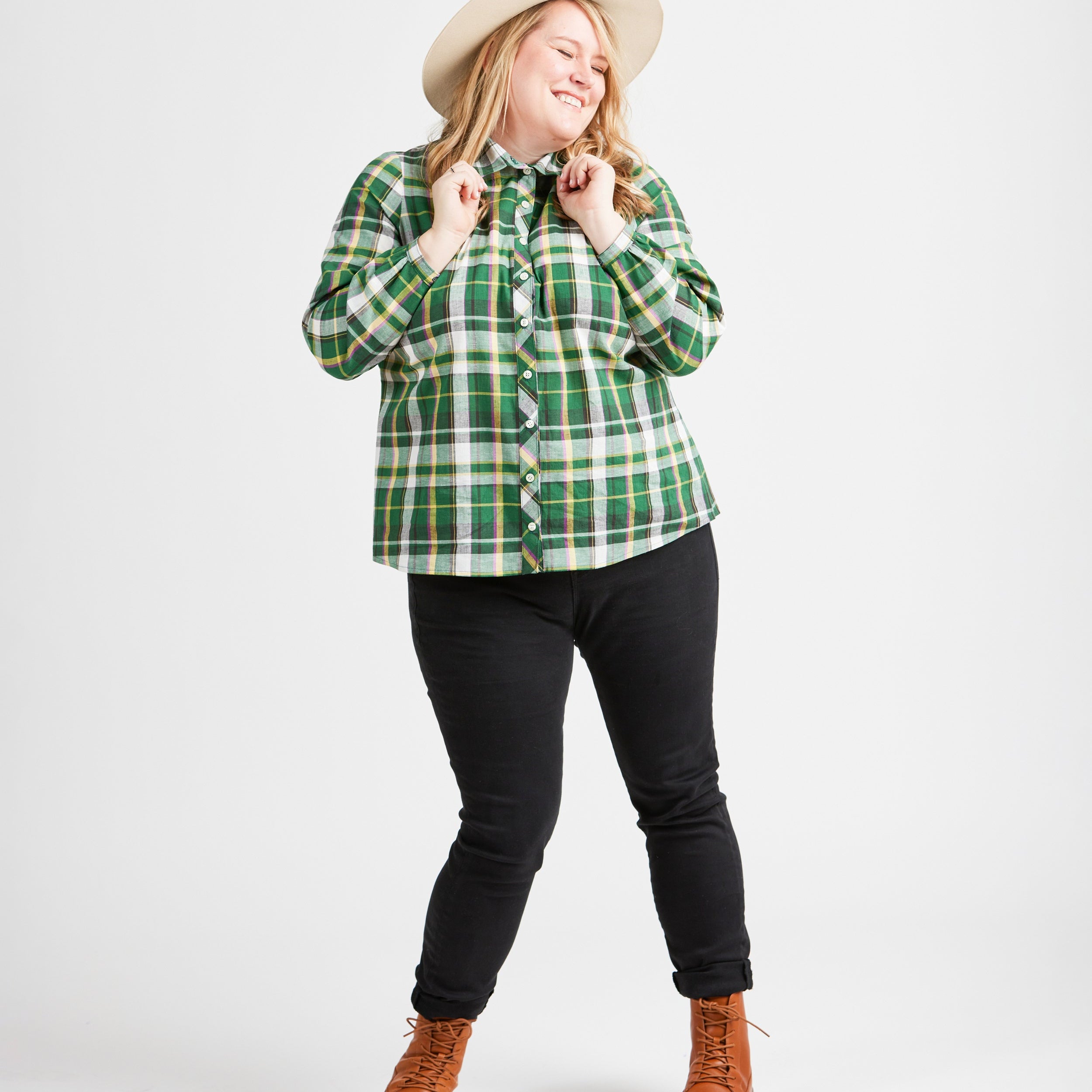 Woman wearing a green plaid shirt, black pants, and brown boots on a white background. This top is the Vernon Shirt sewing pattern from Cashmerette.