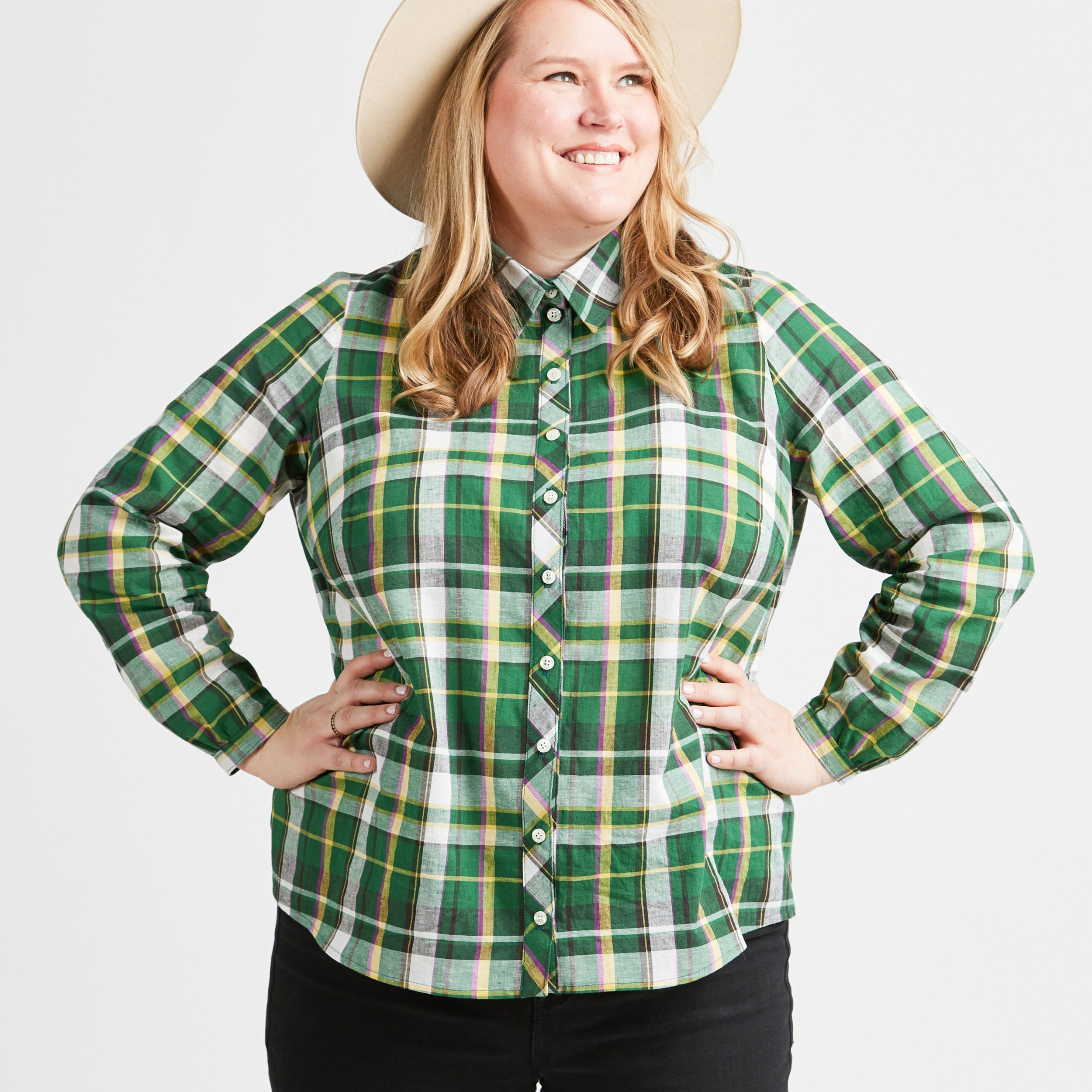 Woman wearing a green plaid shirt and a beige hat on a white background. This top is the Vernon Shirt sewing pattern from Cashmerette.