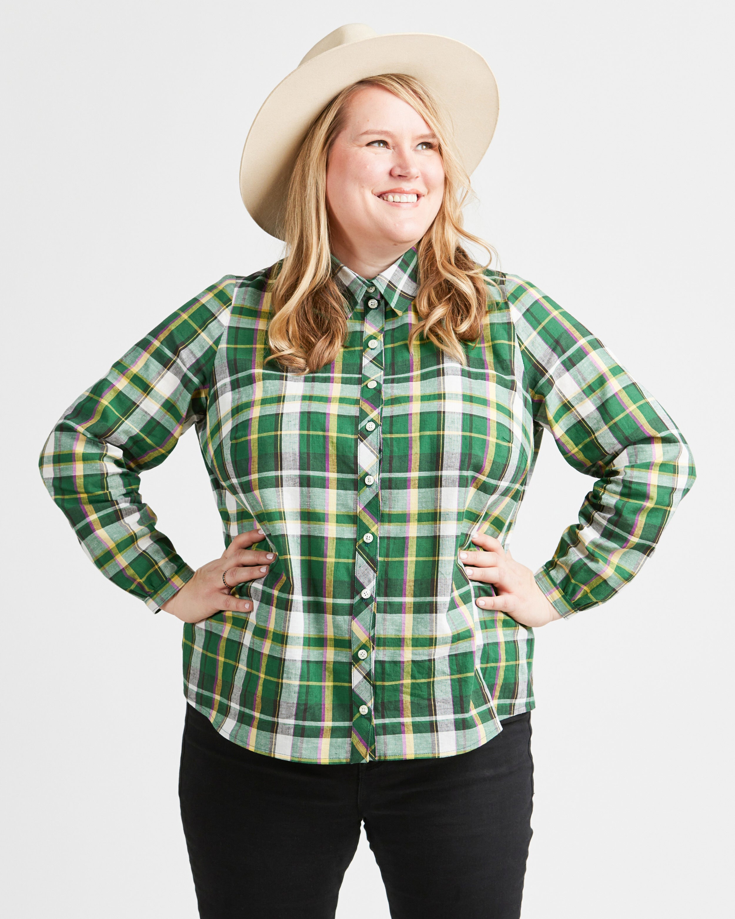 Woman wearing a green plaid shirt and a beige hat on a white background. This top is the Vernon Shirt sewing pattern from Cashmerette.